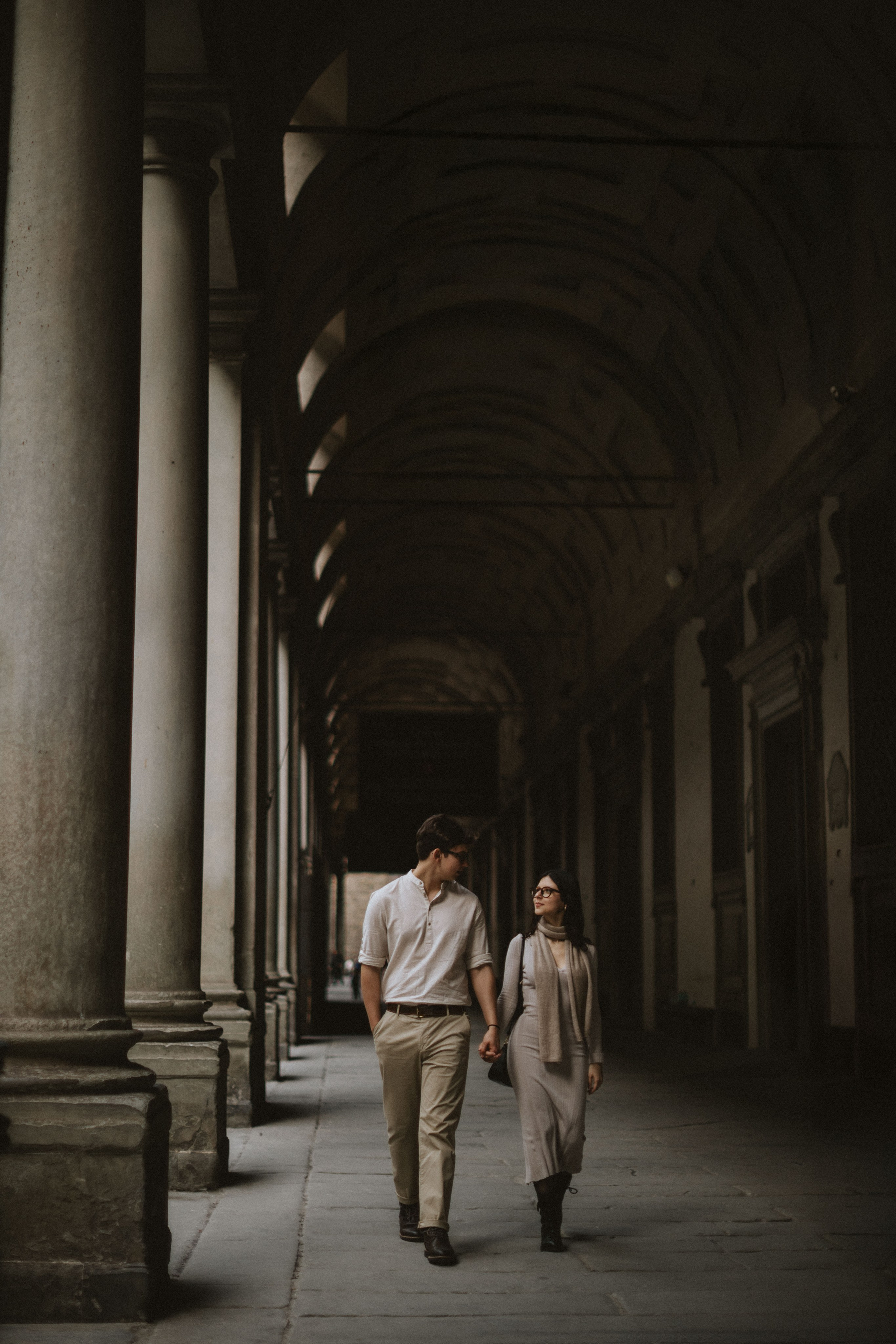 “Una coppia cammina mano nella mano in un corridoio affascinante, scambiandosi sguardi d'amore”.