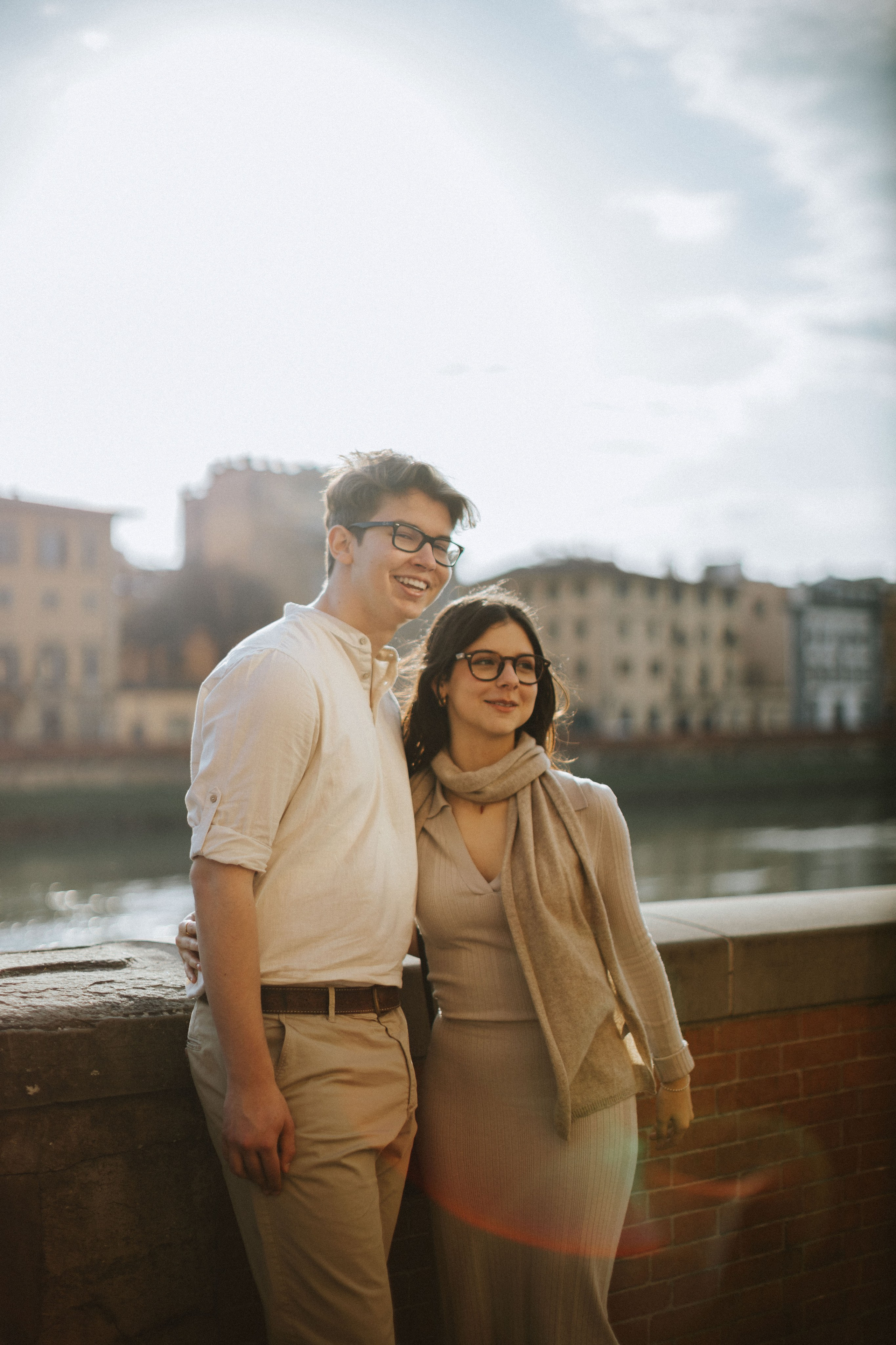 “Una coppia che si gode una giornata di sole in riva al fiume, sorridendo e posando insieme a Firenze”.