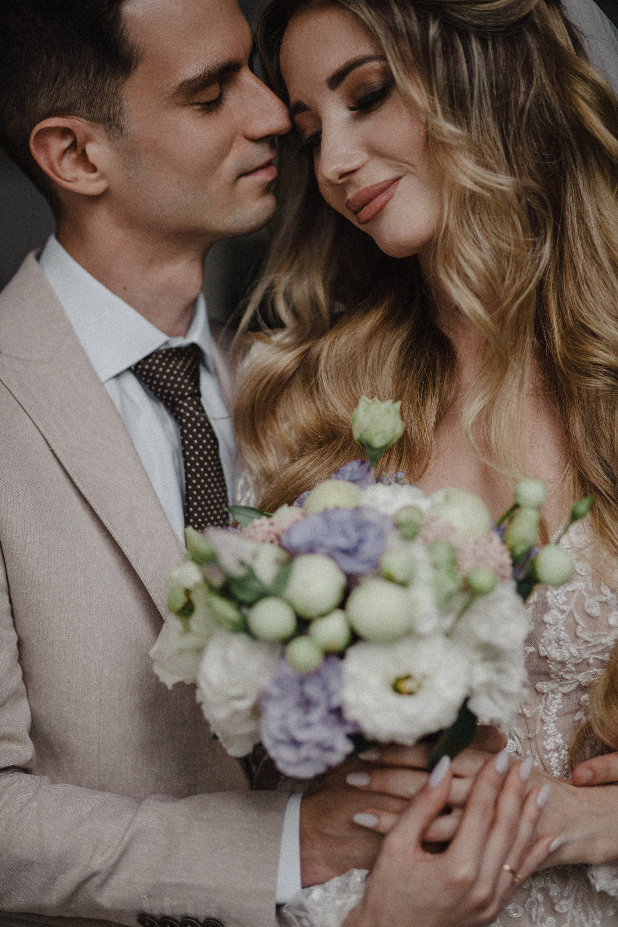 “Fotografo di matrimonio che cattura un momento romantico tra gli sposi, con la sposa che tiene in mano un bellissimo bouquet di fiori bianchi e viola. La coppia, abbracciata e con lo sguardo rivolto all'altro, emana amore e felicità, perfetta per un matrimonio in Toscana in Italia.”