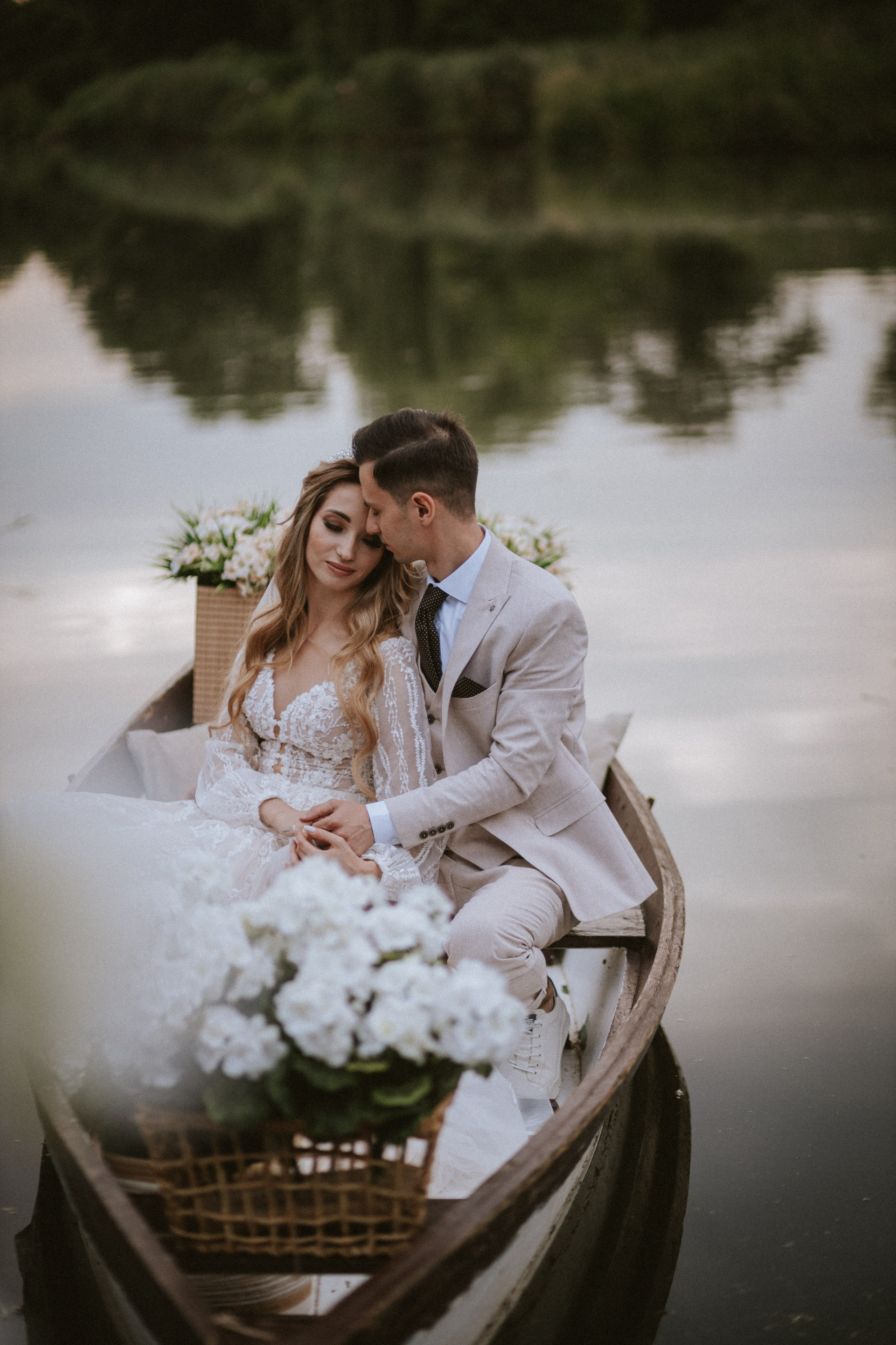 “Coppia romantica in barca circondata da fiori, che si abbraccia e si gode il proprio momento di intimità su un lago sereno”.