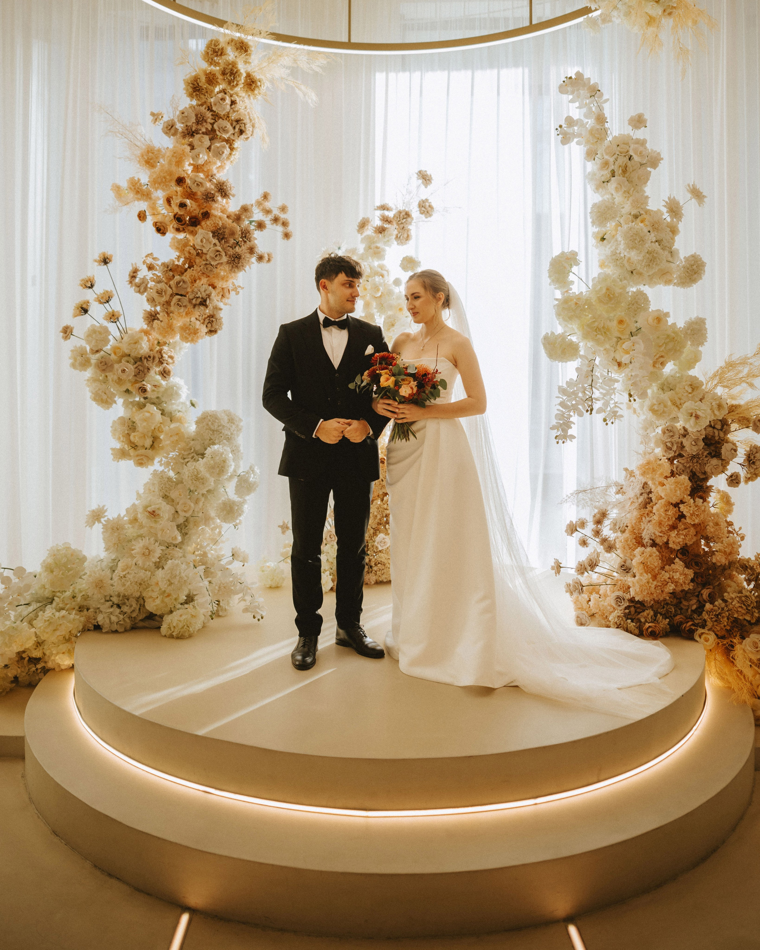 “The bride and groom at the wedding ceremony with floral arrangements in the background, a wedding in one of Italy’s most stylish cities, such as Milan or Rome.”