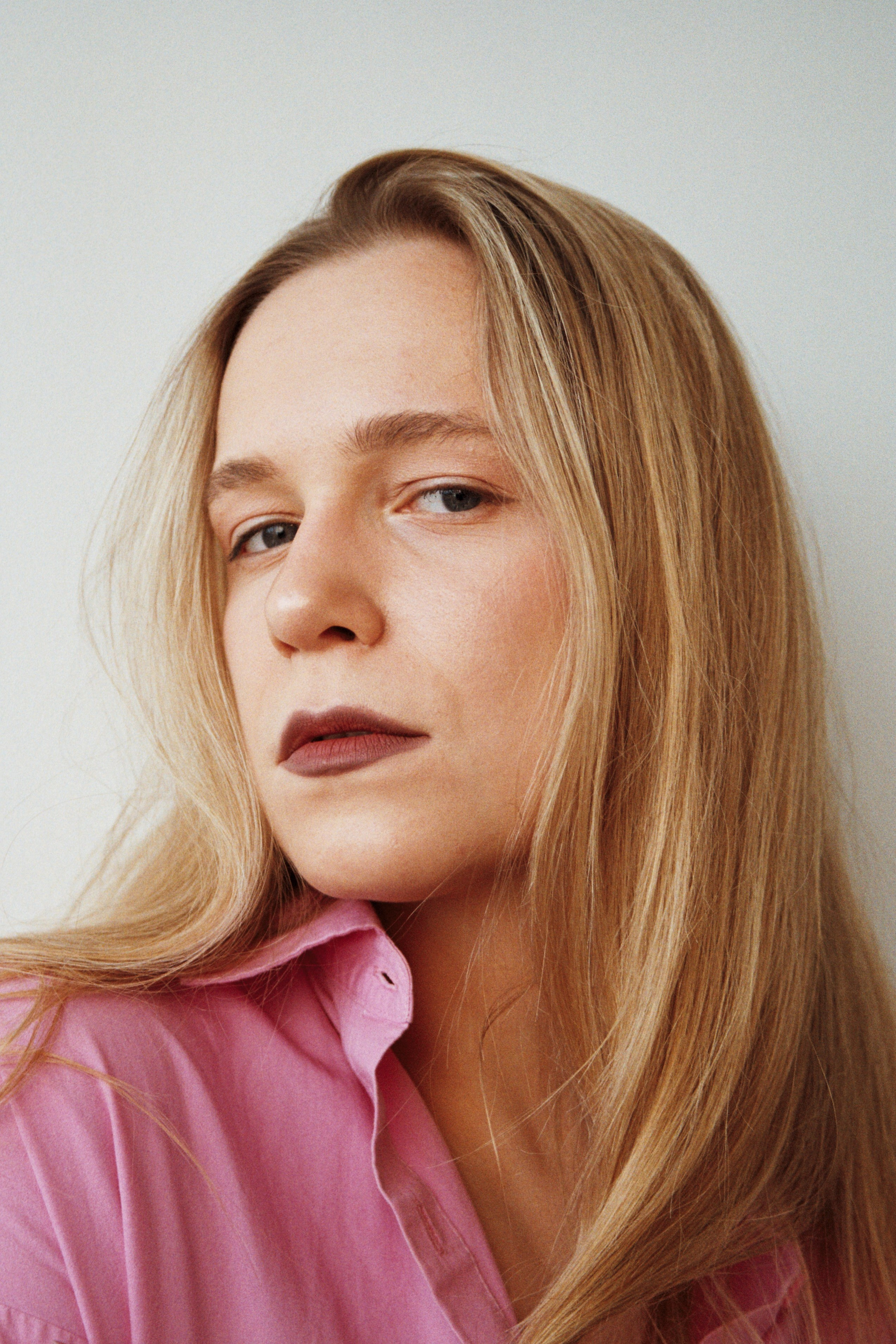 Minimalist composition portrait in a brightly lit white studio space, clean aesthetic on 35mm analog film.