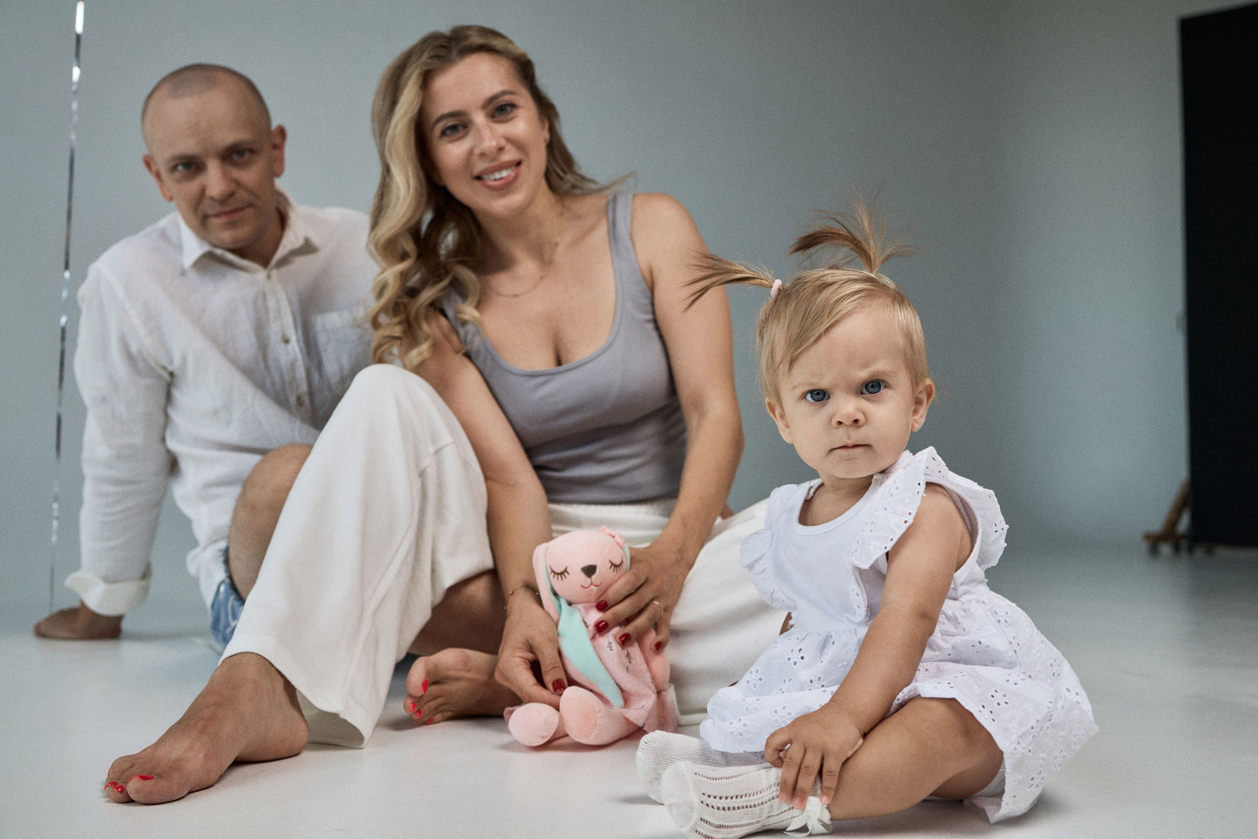 Сімейний портрет у студії — мама, тато й дитина з іграшкою фотограф