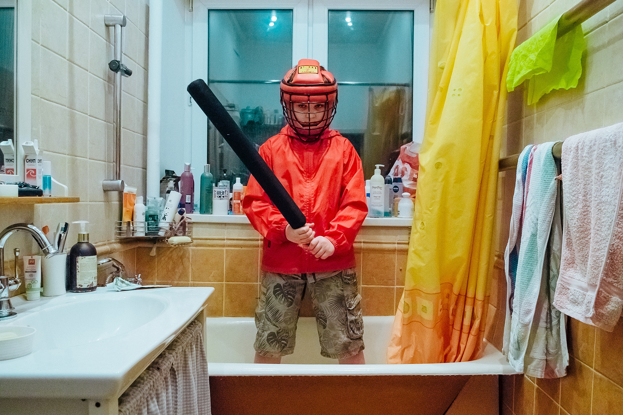 A boy in a helmet stands with a bat in his hands. Мальчик в шлеме стоит с битой в руках.