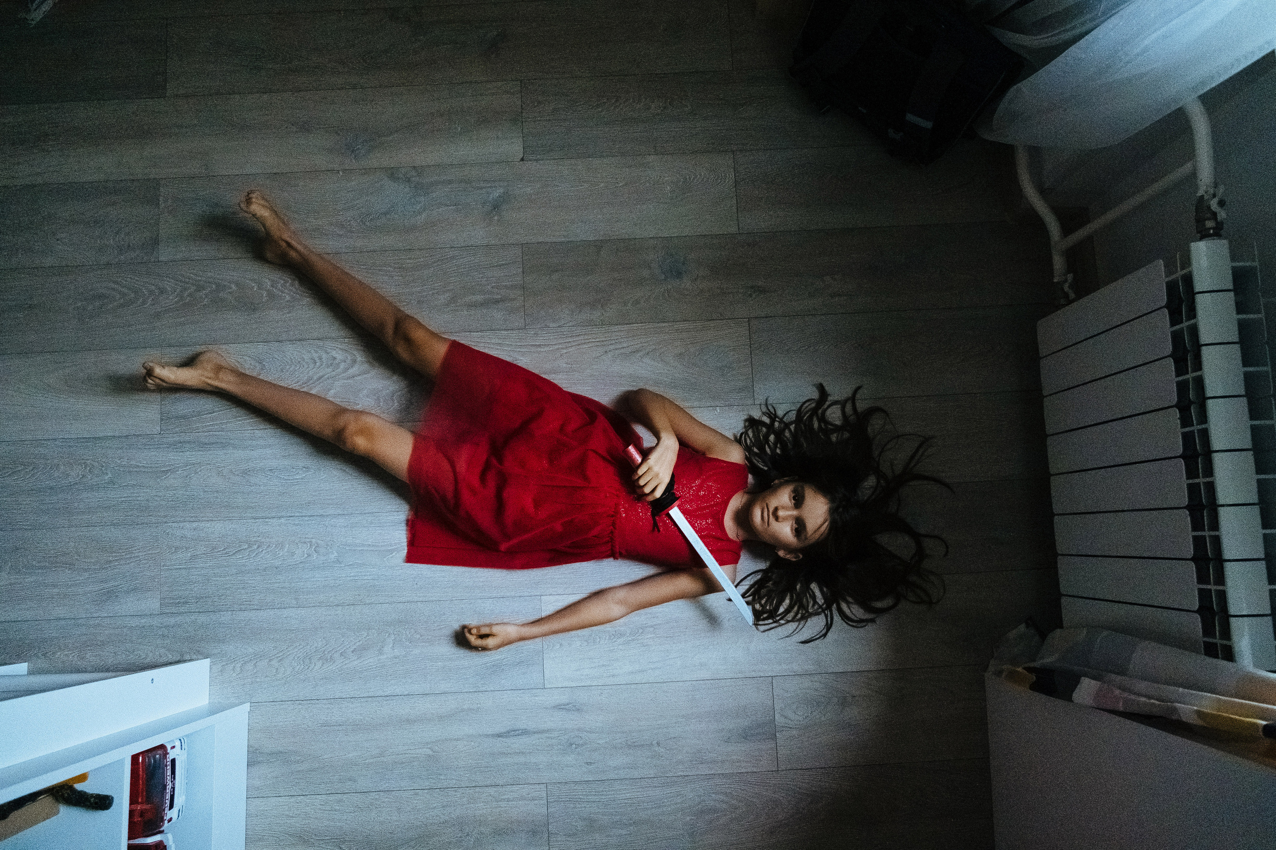 The girl is lying on the floor and holding a dagger in her hands. Девочка лежит на полу и держит кинжал в руках.