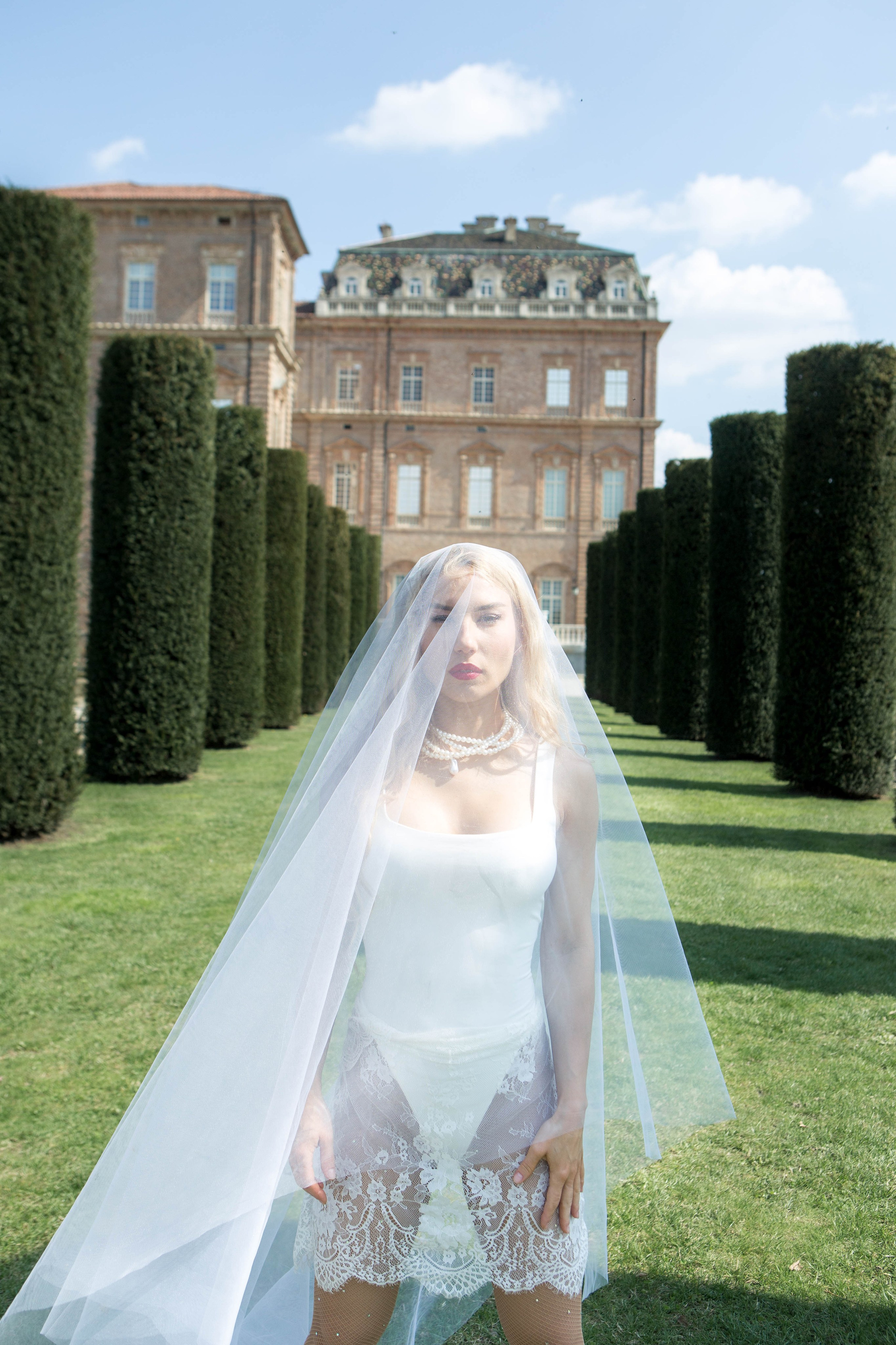 Bride posed beneath her veil in front of an elegant Italian villa, artfully captured by wedding photographer in Italy, Irina Armonìa
