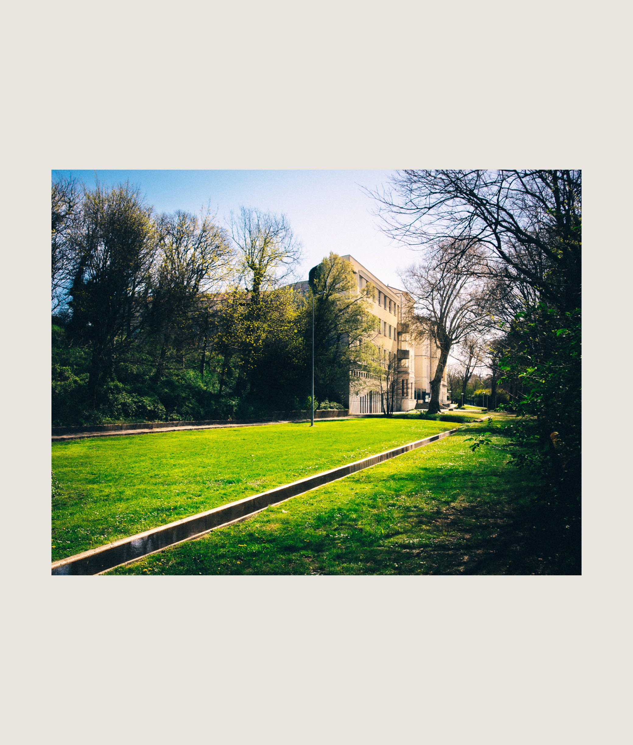 Allée ombragée menant à une vieille maison au cœur d’un parc urbain