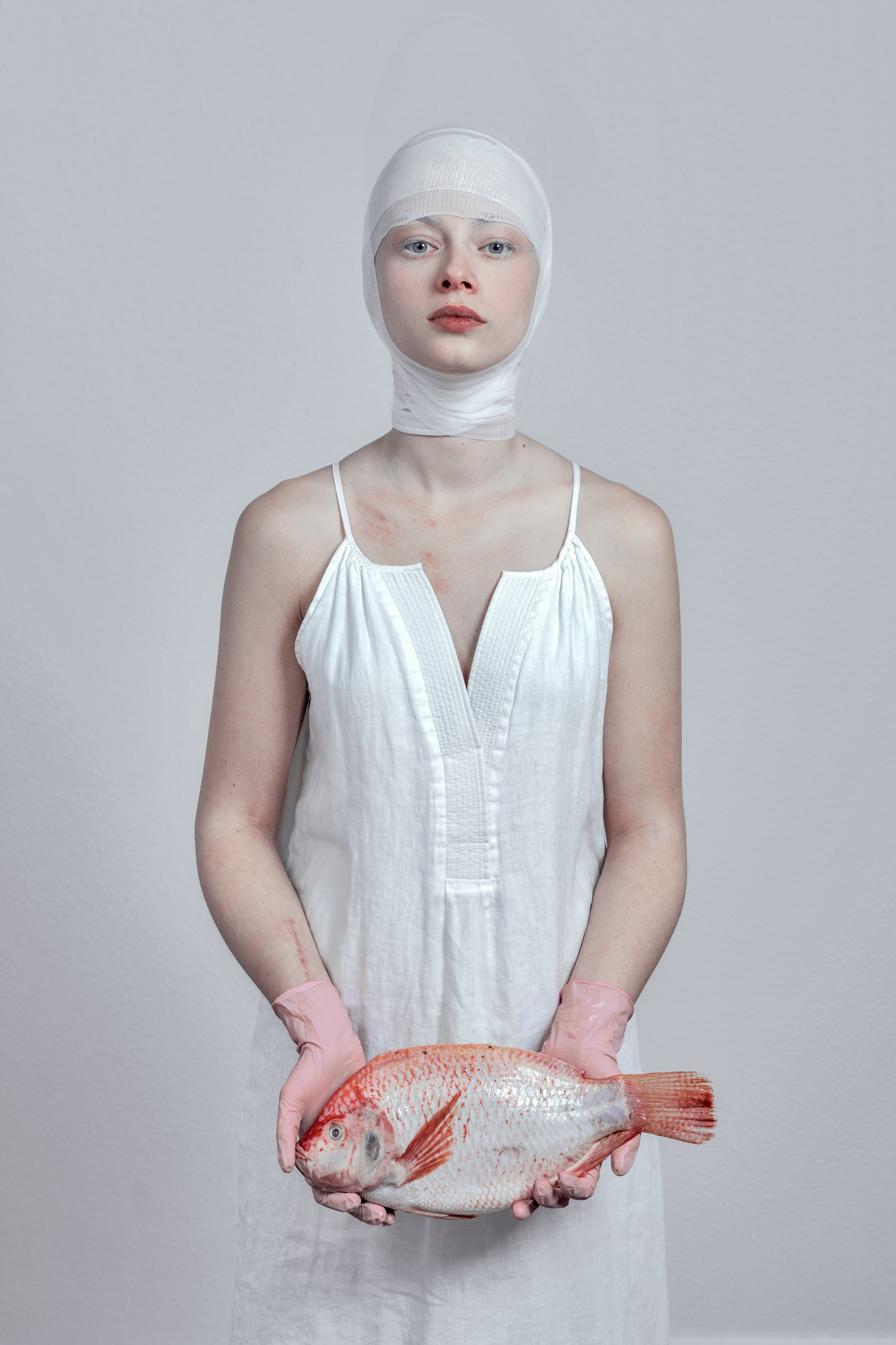 Woman in white holding a fish, symbolizing new beginnings in a strange land.