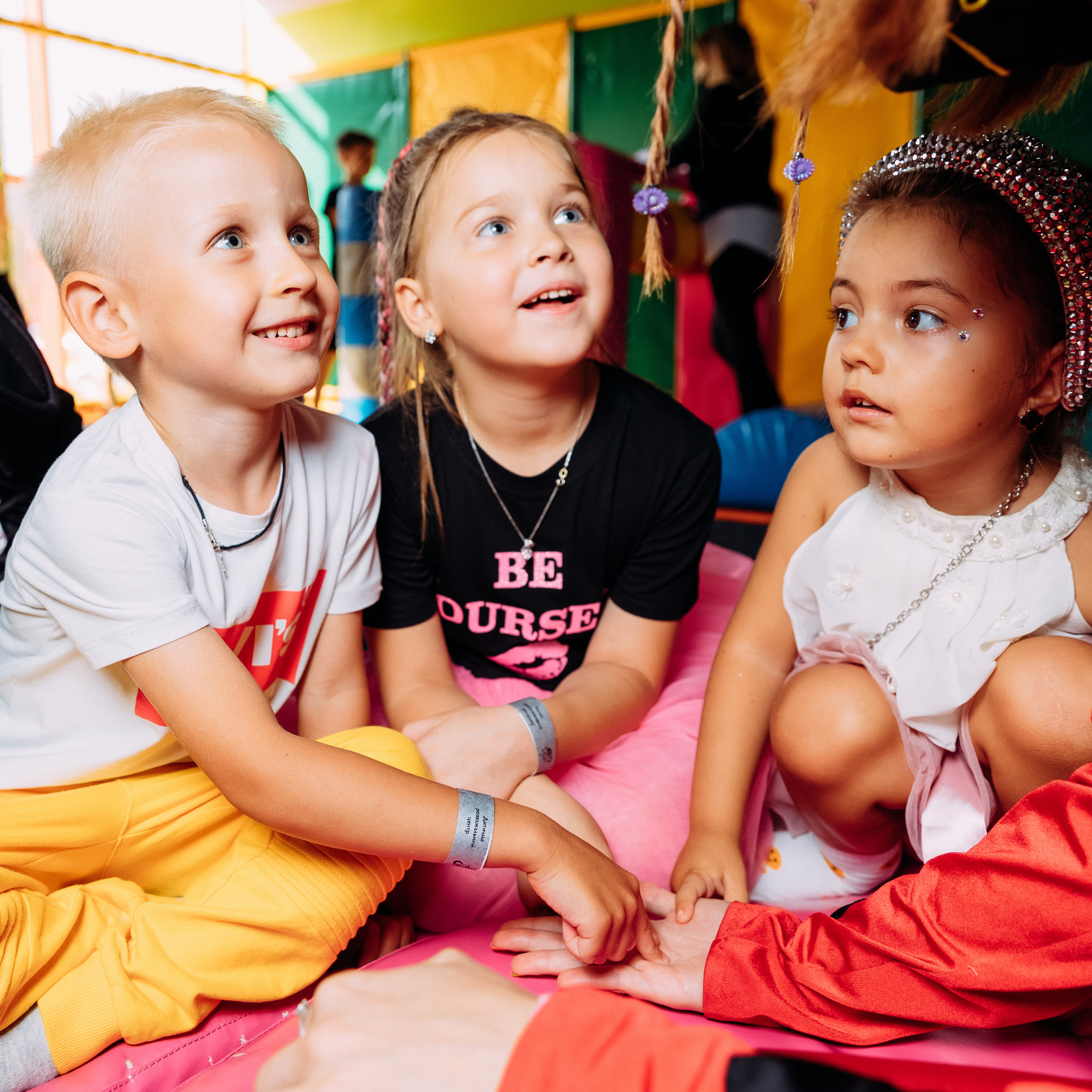 Две мальчика и девочка сидят на полу с разными эмоциями.