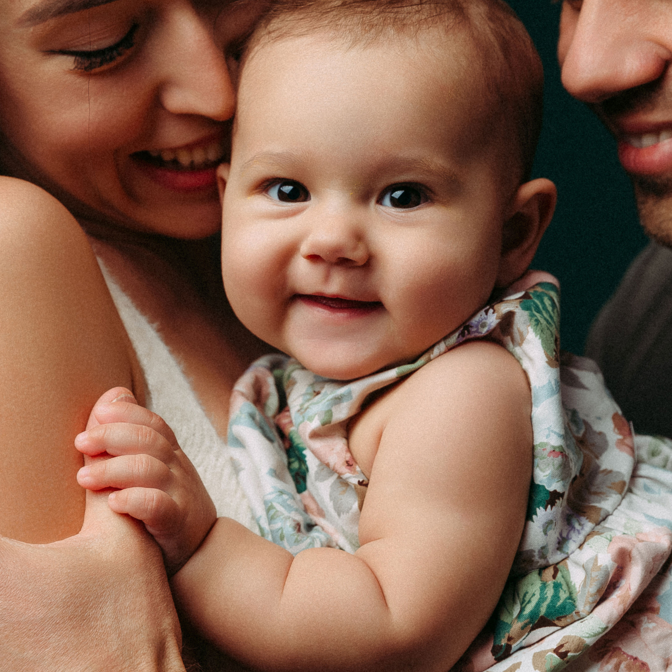 Папа и мама держат на руках свою маленькую дочку.