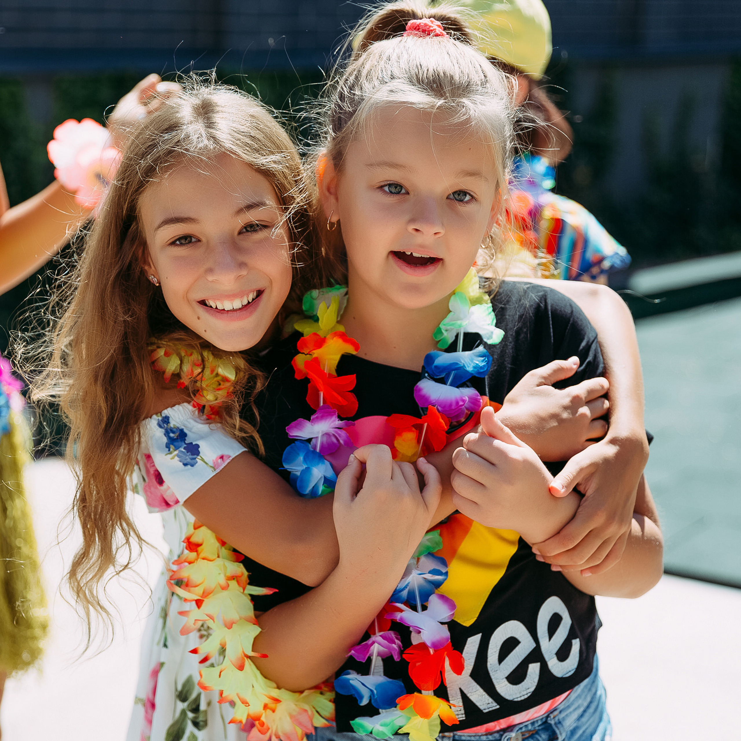 Две девочки обнимаются и смеются.