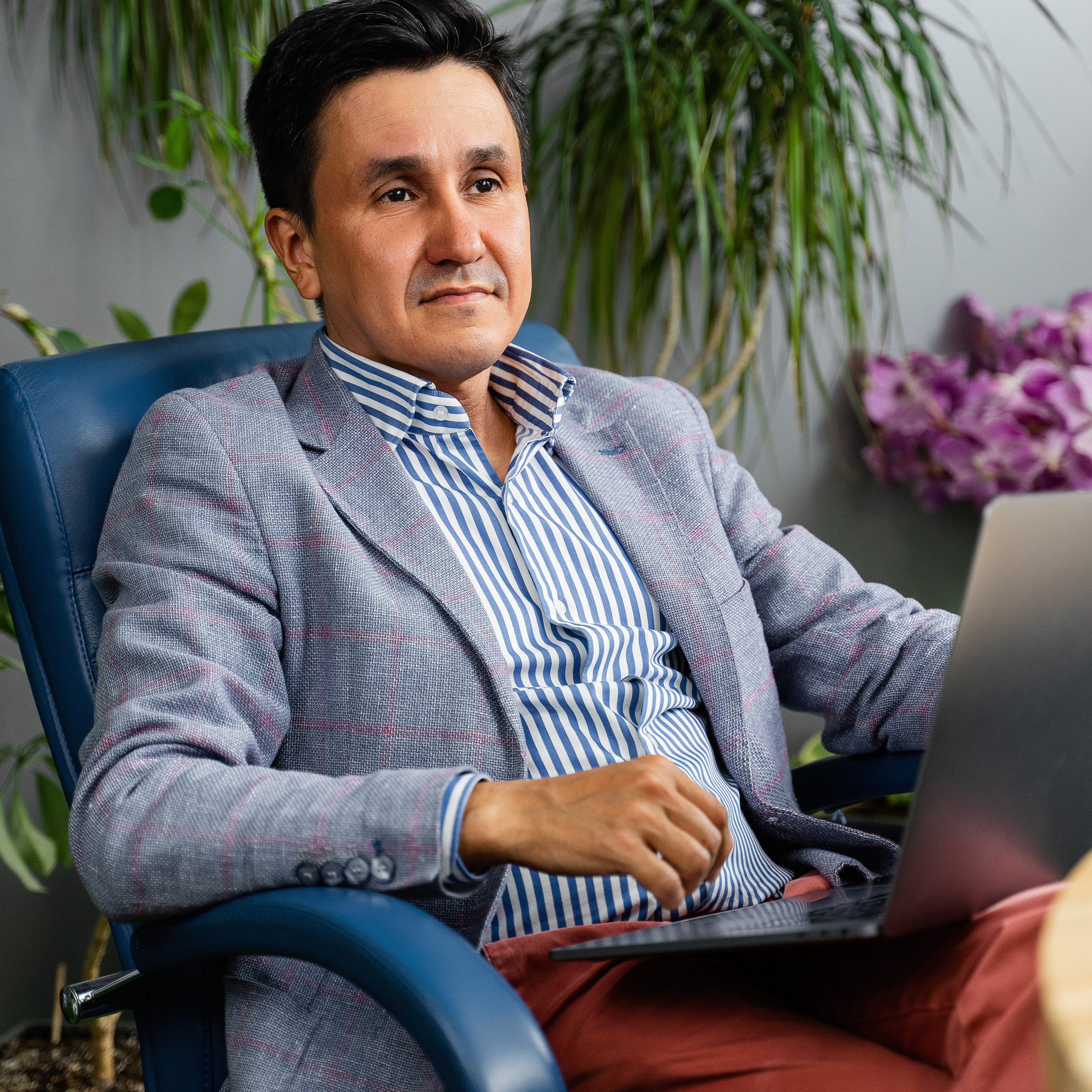 Business executive in a patterned suit, working on a laptop in a modern office environment, for corporate promotion