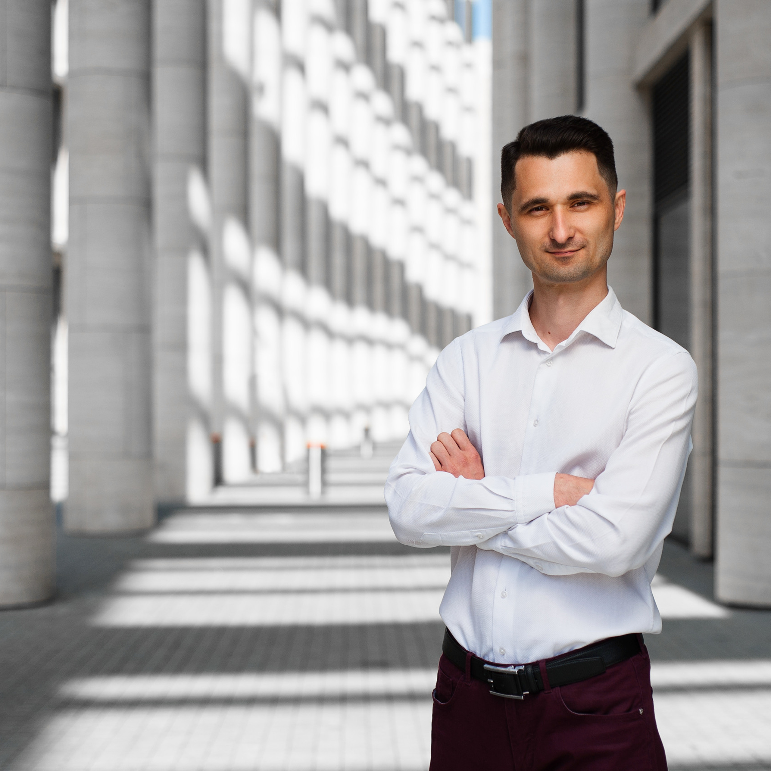 Confident business professional standing with folded arms in a corporate environment, a corporate portrait by Dmitrii Shmatov.