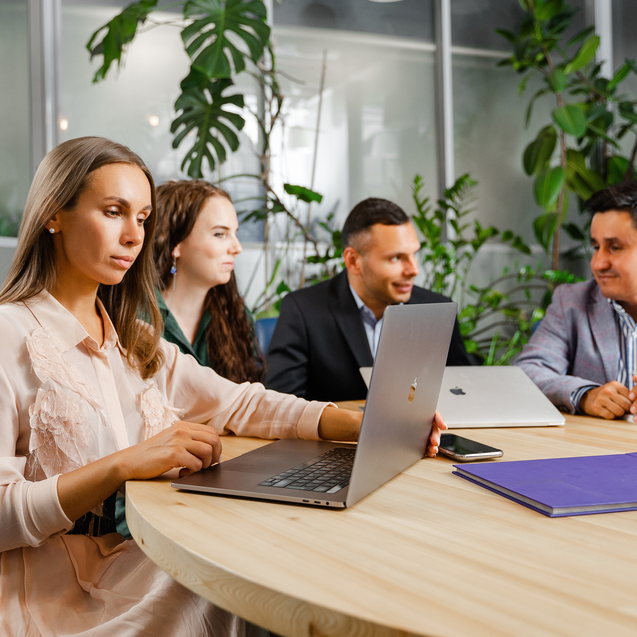 Business professionals in a collaborative meeting in a modern office setting with lush greenery, captured by photographer Dmitrii Shmatov