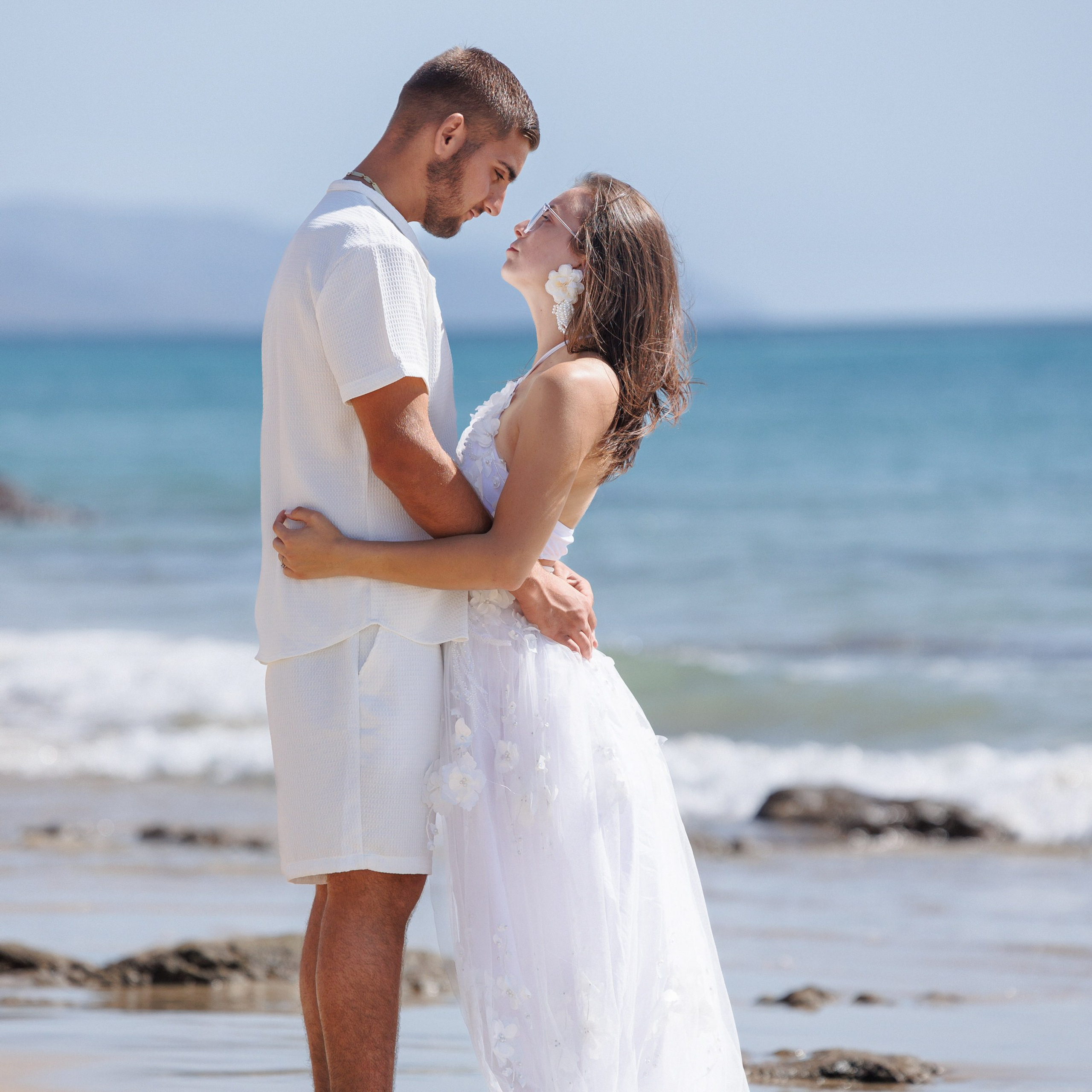A serene morning beach walk with a couple hand in hand, the tranquil ocean in the background. Fuerteventura's stunning coastline adds a peaceful backdrop to this intimate love story session.