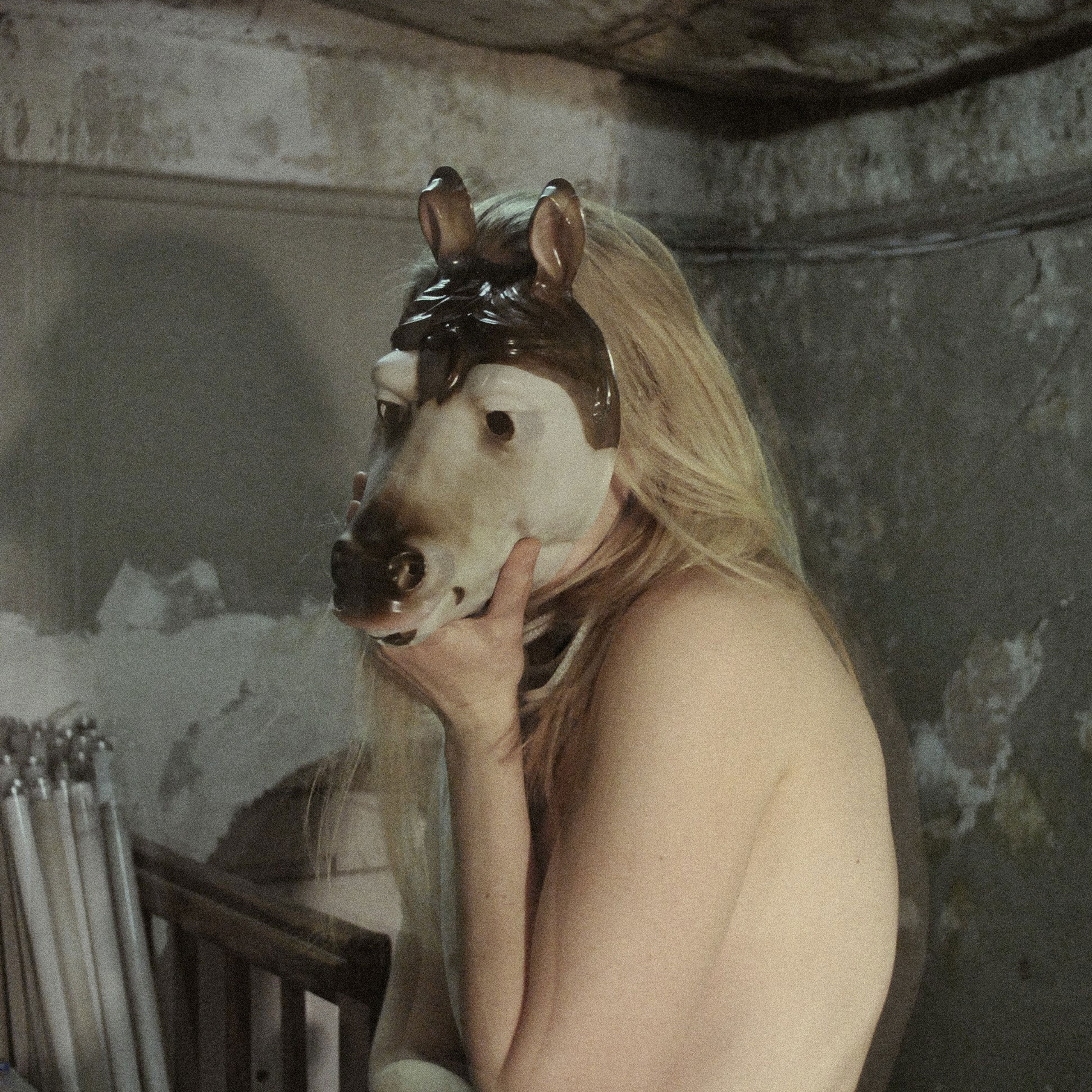 Artistic photograph of a nude female figure with an obscured face, posed in a contemplative stance against a neutral backdrop, from Leni Smoragdova's 'Figures Collection: Past Version' (2020).