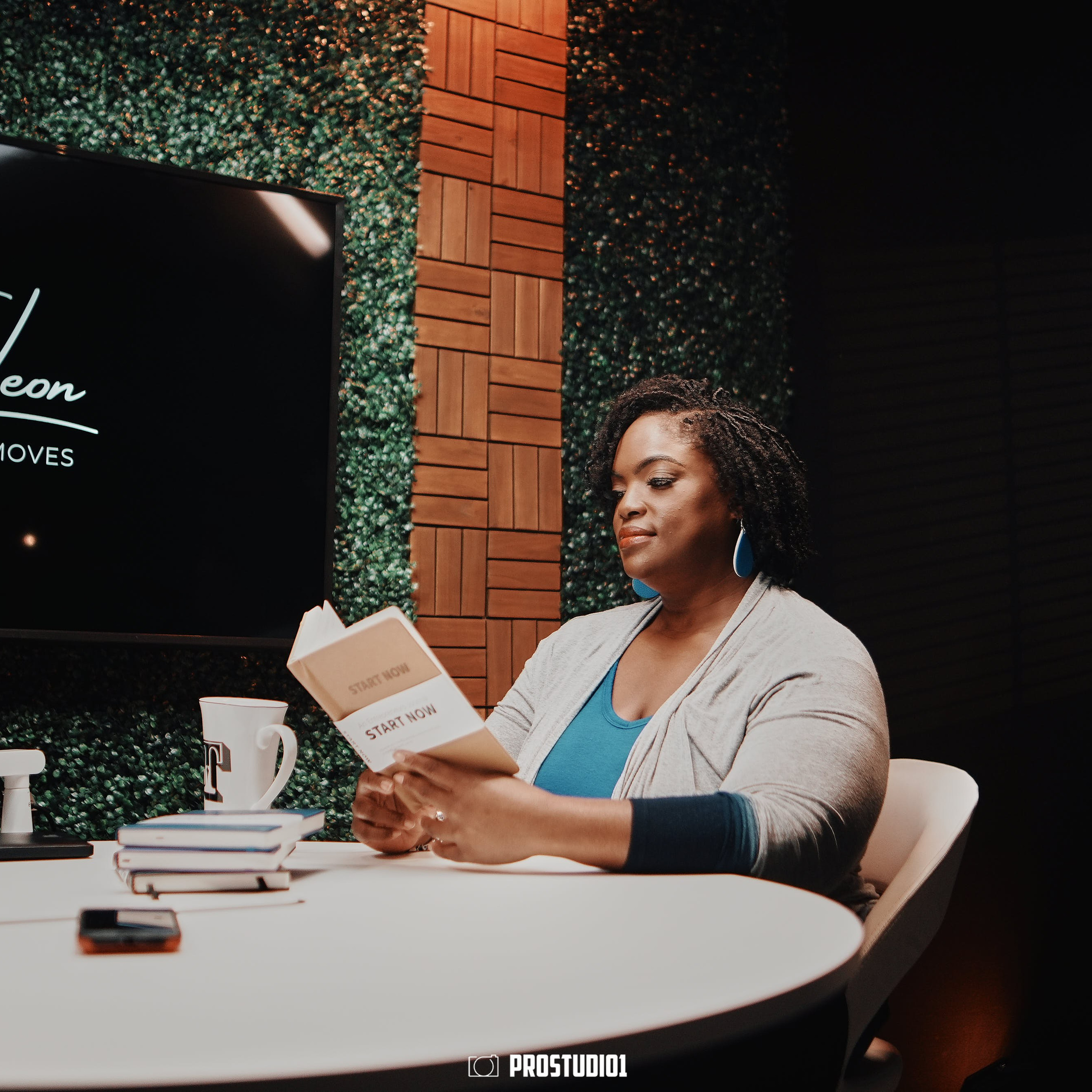 Podcast host setup at ProStudio1 in Hollywood, FL — guest at round table with microphone and studio monitor in talk-show set.