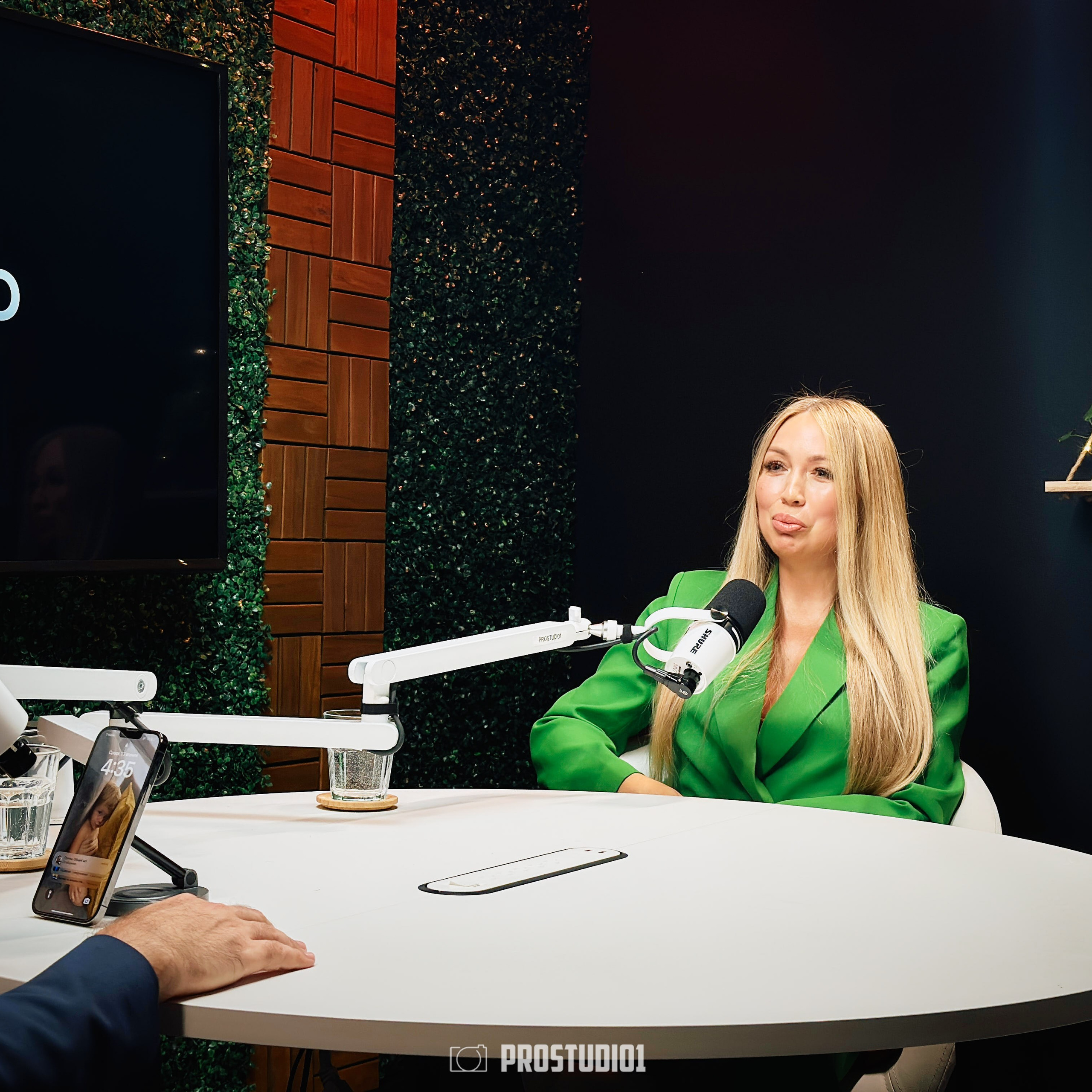 Two-person podcast interview at ProStudio1, Hollywood Florida — guest speaking at round table with pro microphone and cinematic background.