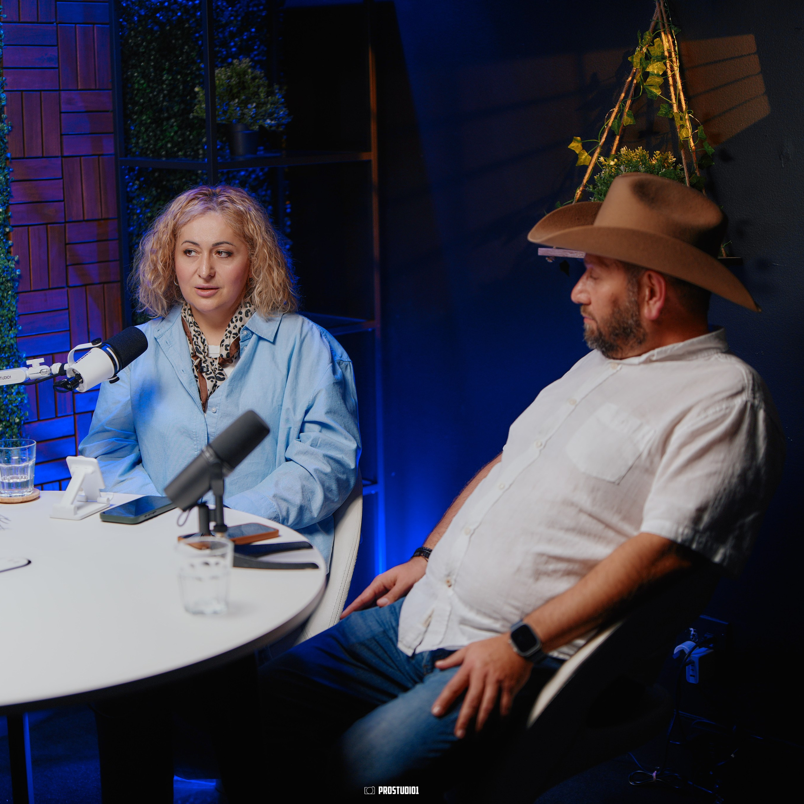 Interview recording environment at ProStudio1 in Hollywood, Florida — talk-show table with studio microphones and cinematic mood lighting.