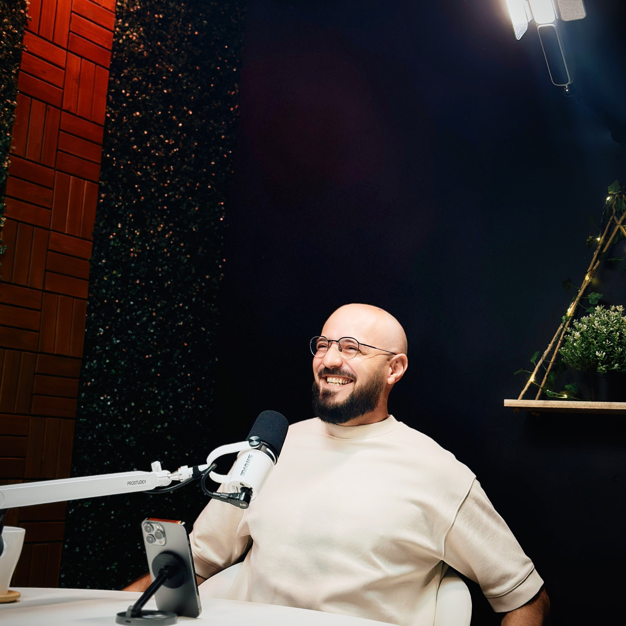Two-person interview setup at ProStudio1 in Hollywood, FL — talk-show table with microphones, headphones, and cinematic background.