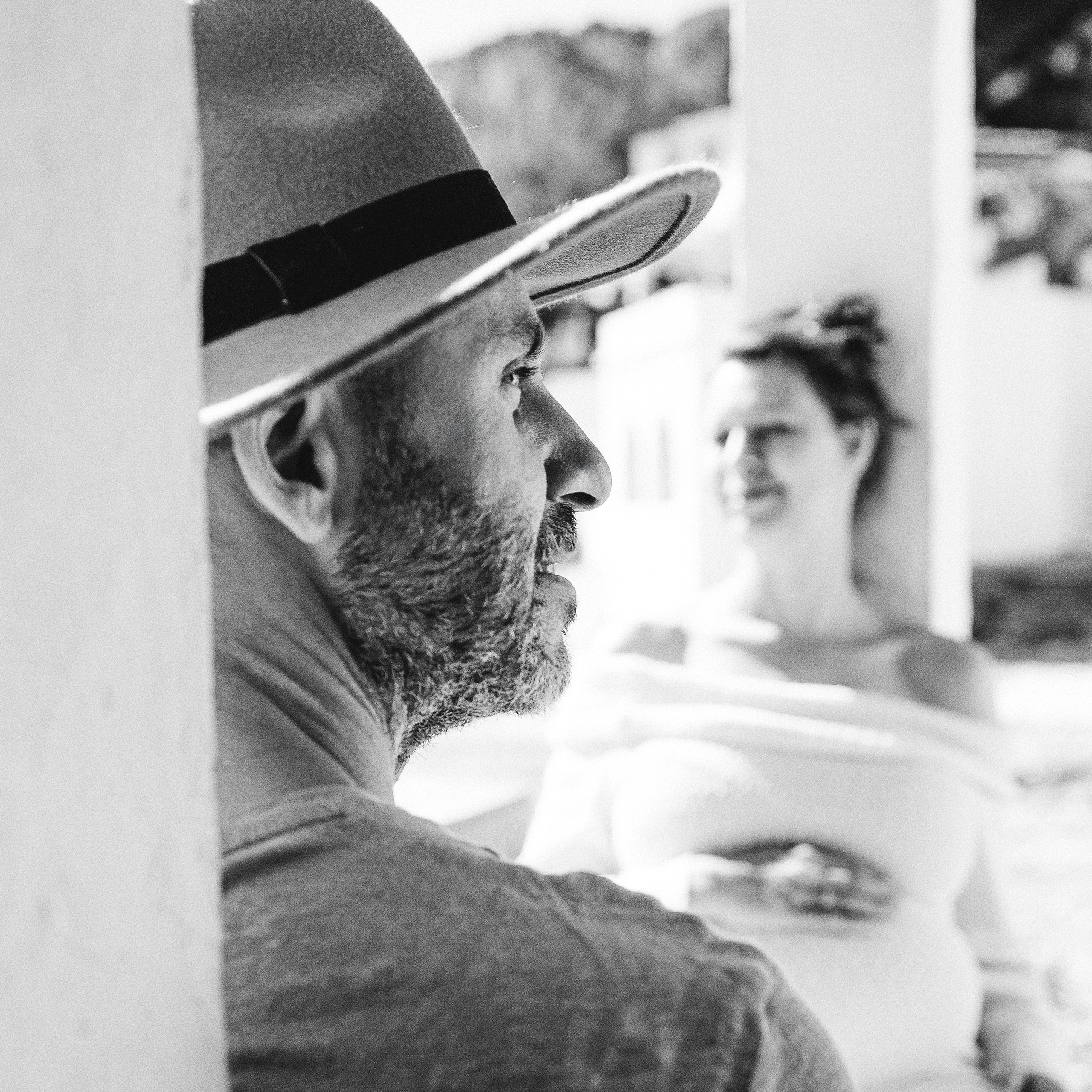 Artistic black and white portrait photo of a bearded man with a smiling woman in the background, in Alicante, Spain