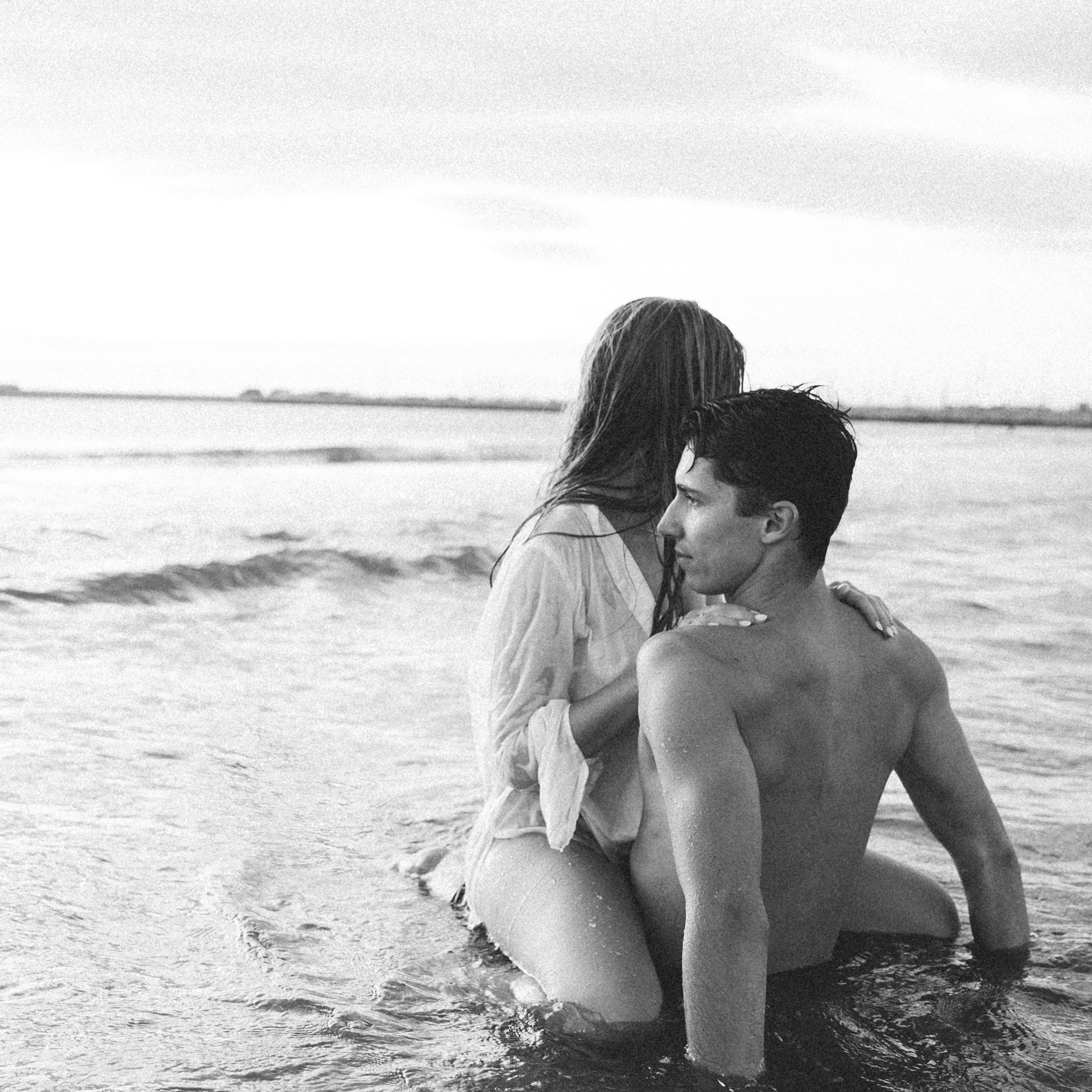 Black and white romantic couple’s beach photoshoot (love story) in the sea in Valencia, Spain