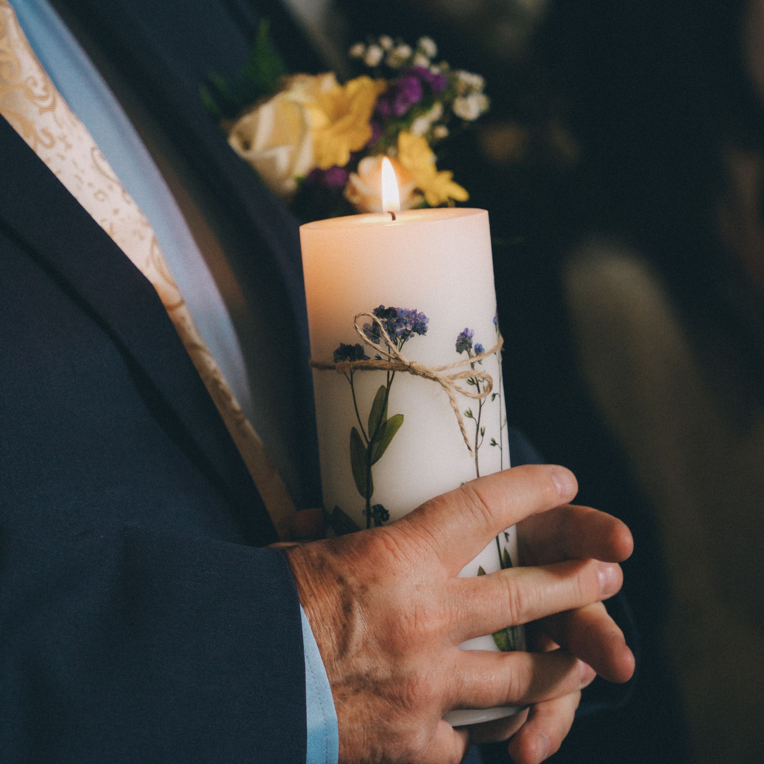 A man holding a candle at the wedding ceremony. Solihull wedding photographer in the church