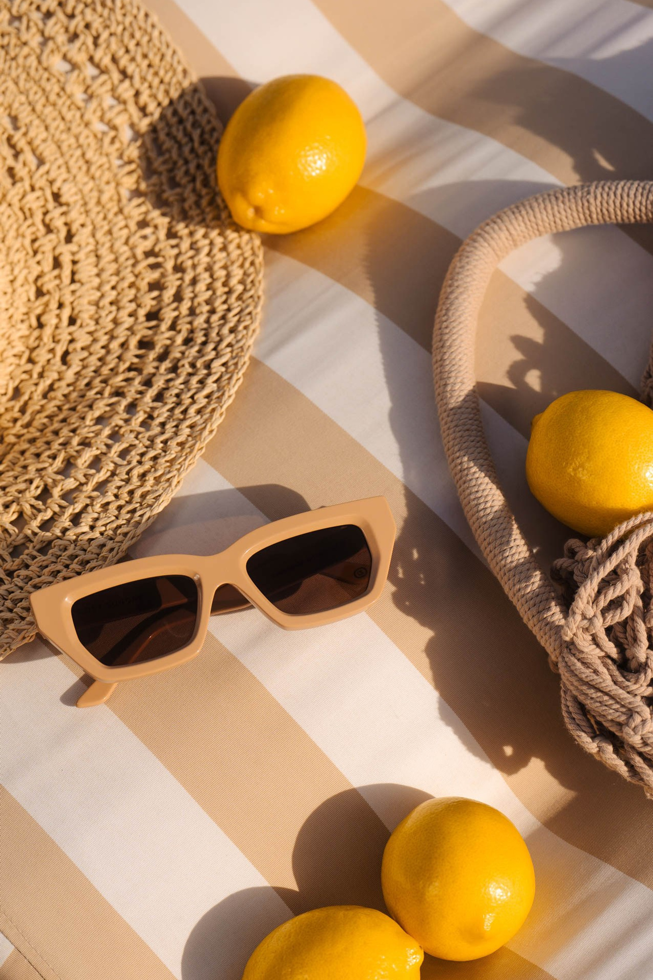 Fashion still life with lemons, sunglasses and woven textures in natural light