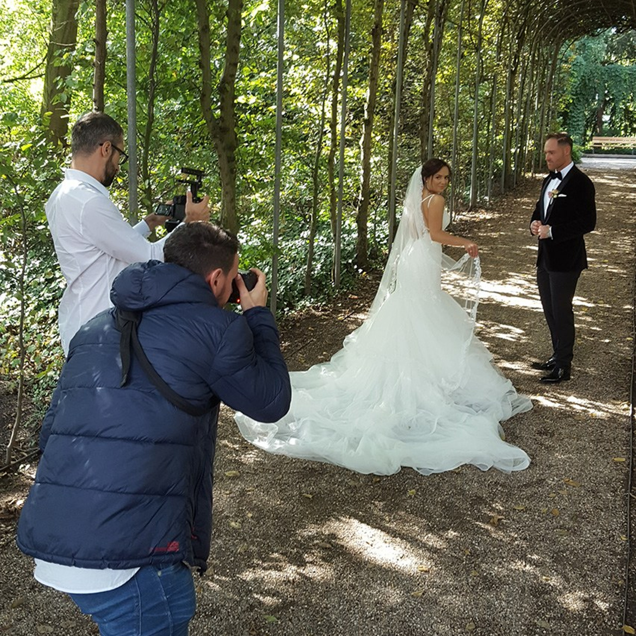 Braut wird durch einen grünen Park geführt – romantische Hochzeitsaufnahmen im Freien