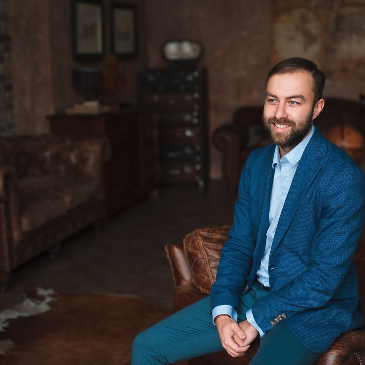Casual corporate portrait of a man in a blue suit seated in a vintage office setting by Dmitrii Shmatov