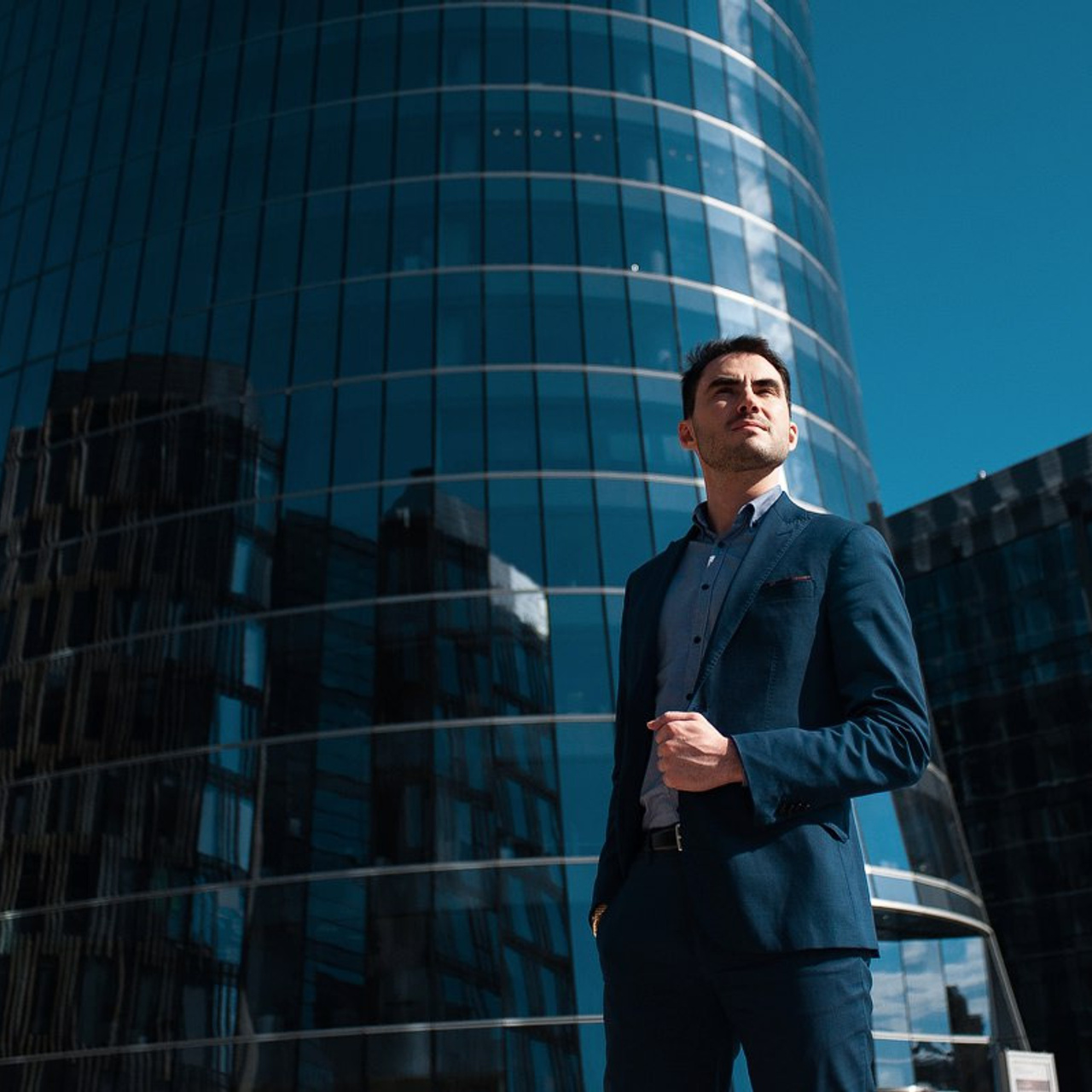 Outdoor corporate headshot by Dmitrii Shmatov against a modern building backdrop for business profiles