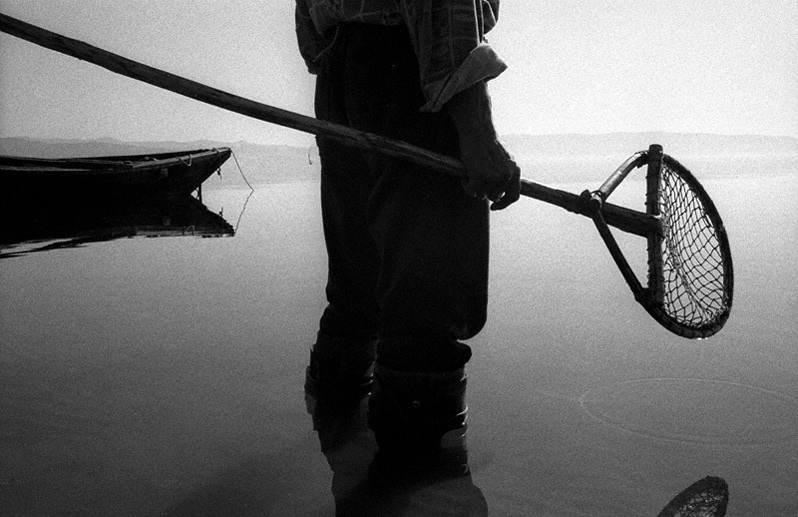 Силуэт рыбака на фоне озера Байкал. Берег мыса Покойники, близ посёлка Курбулик, Баргузинский район, Бурятия, Россия. Октябрь 2001