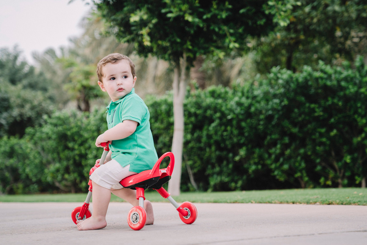 Photo of a boy riding a red bicycle in a park