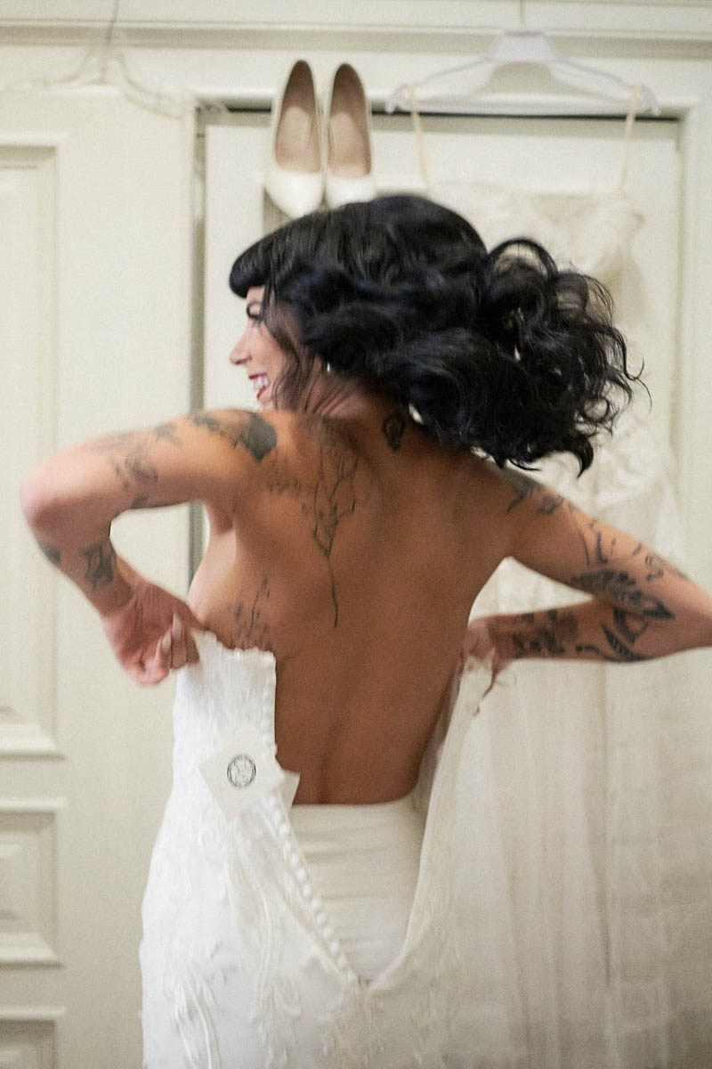 Bride laughing delightedly while slipping into gothic wedding dress.