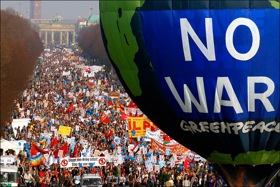 A balloon emblazoned with 'No War' looms above a crowd of tens of thousands of anti-war protestors who are marching from Berlin's Brandenburg Gate.