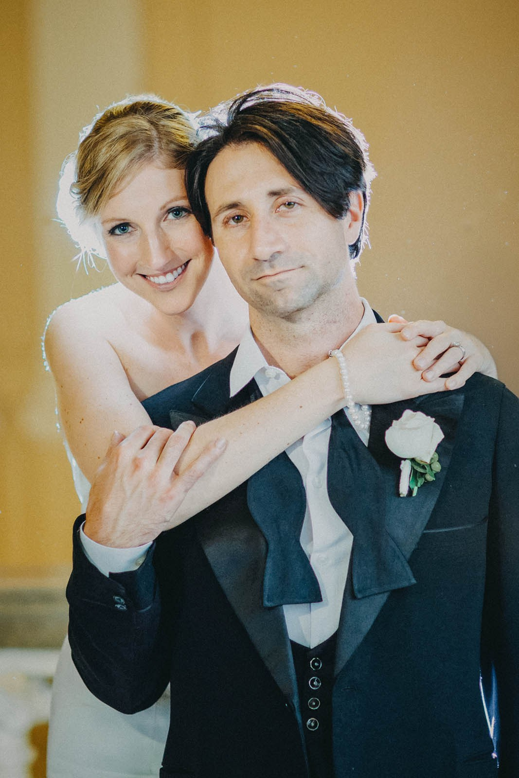 Portrait of a groom with bowtie undone and his blonde-haired bride