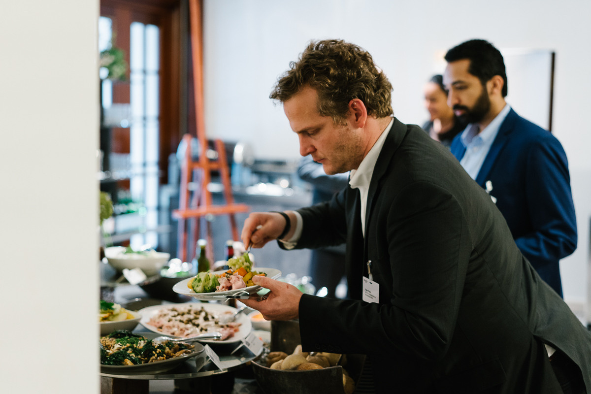Guest in suit taking food from buffet at networking reception during corporate event