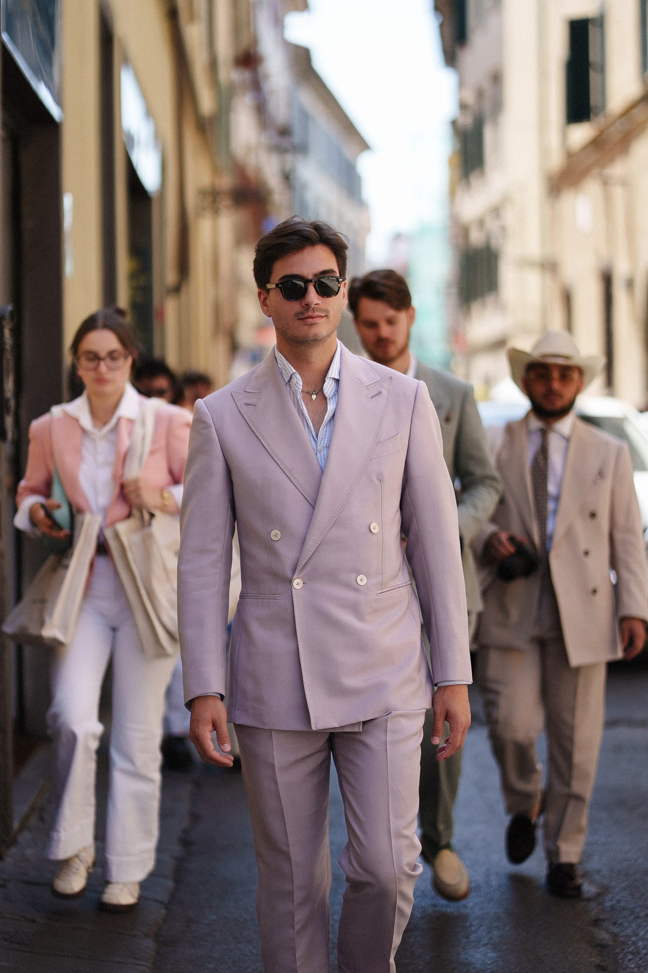 Ritratto street style da Pitti Uomo 110, ospite in completo lilla chiaro che cammina a Firenze durante la fiera