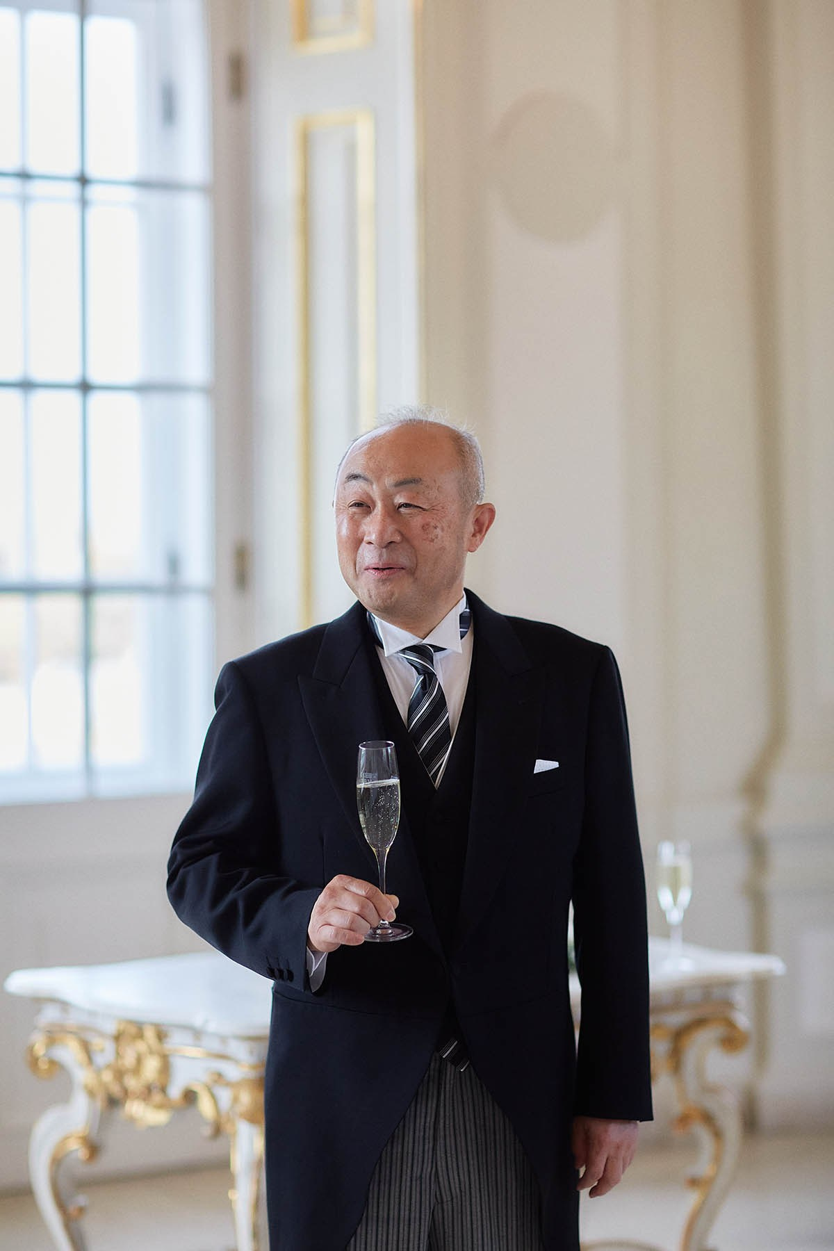 Proud father with champagne flute toasting at intimate Vienna wedding.