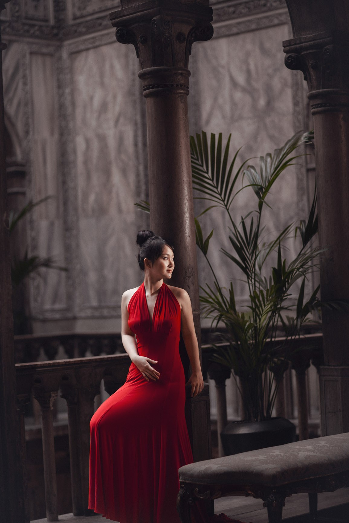 A Thai woman wearing a sexy red evening dress poses inside the historic interior of the Hotel Danieli in Venice during her destination Love Story portrait session.