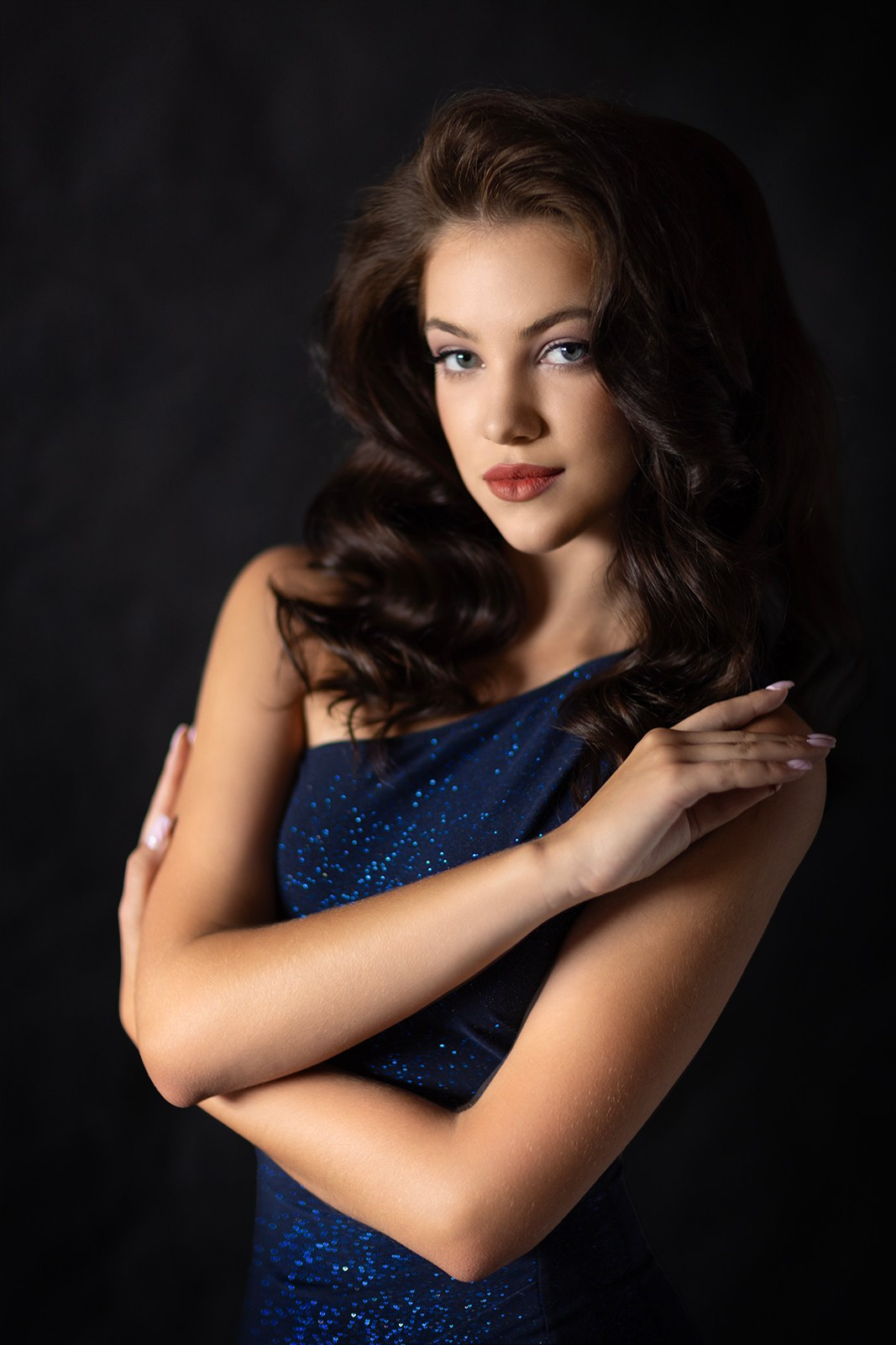 Портрет с чувственным взглядом в синем платье на чёрном фоне