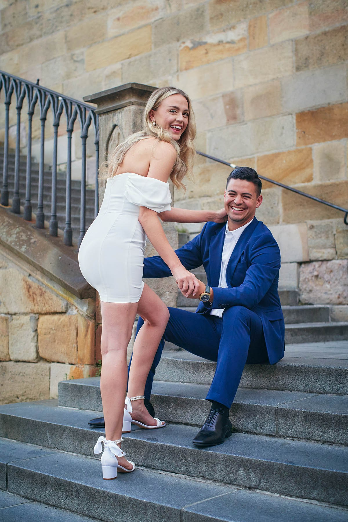 Engaged California couple sharing playful laughter on charming Kampa Steps in dawn light.