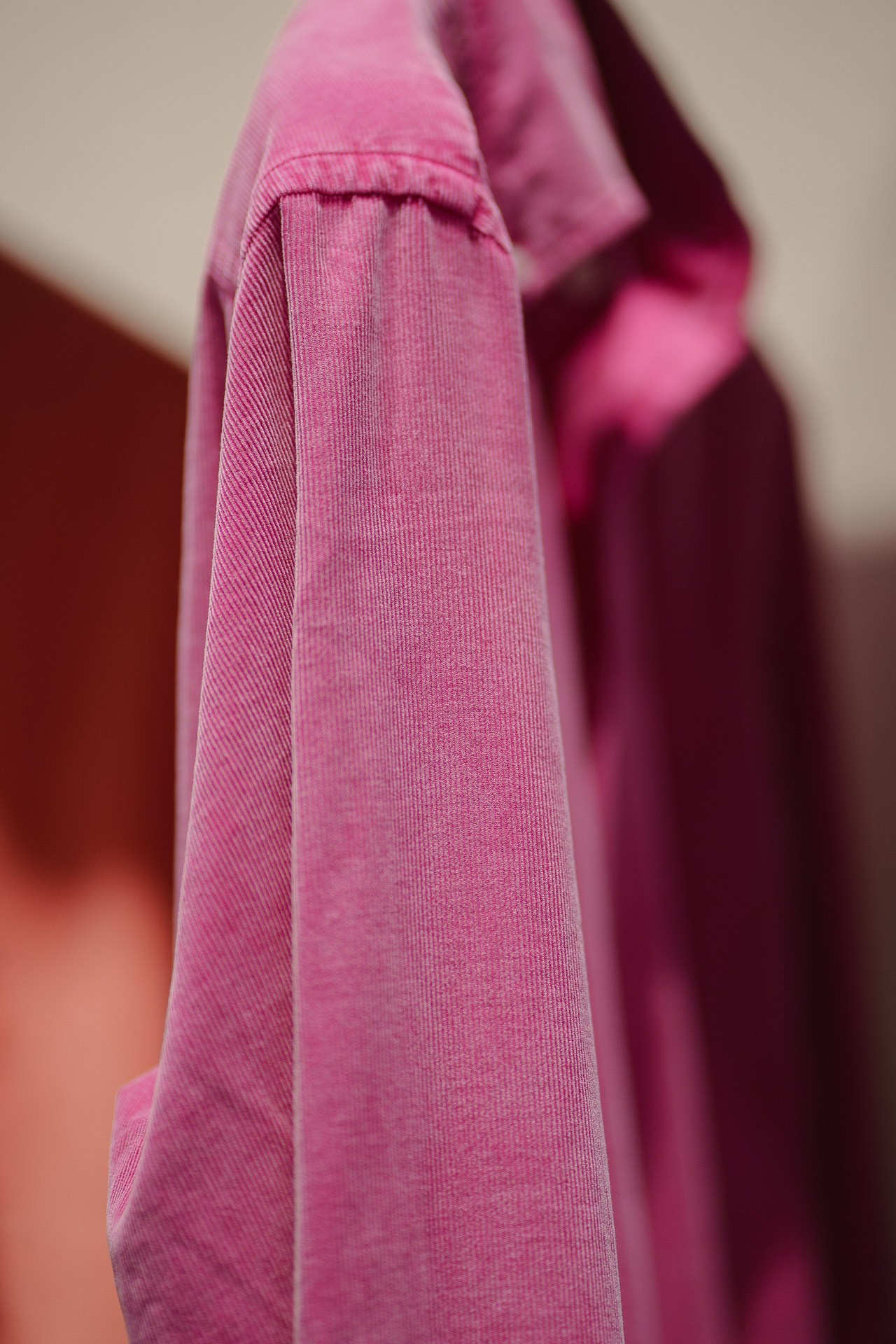 Close-up of a purple corduroy shirt cuff, showing the exquisite button detail and fabric quality.