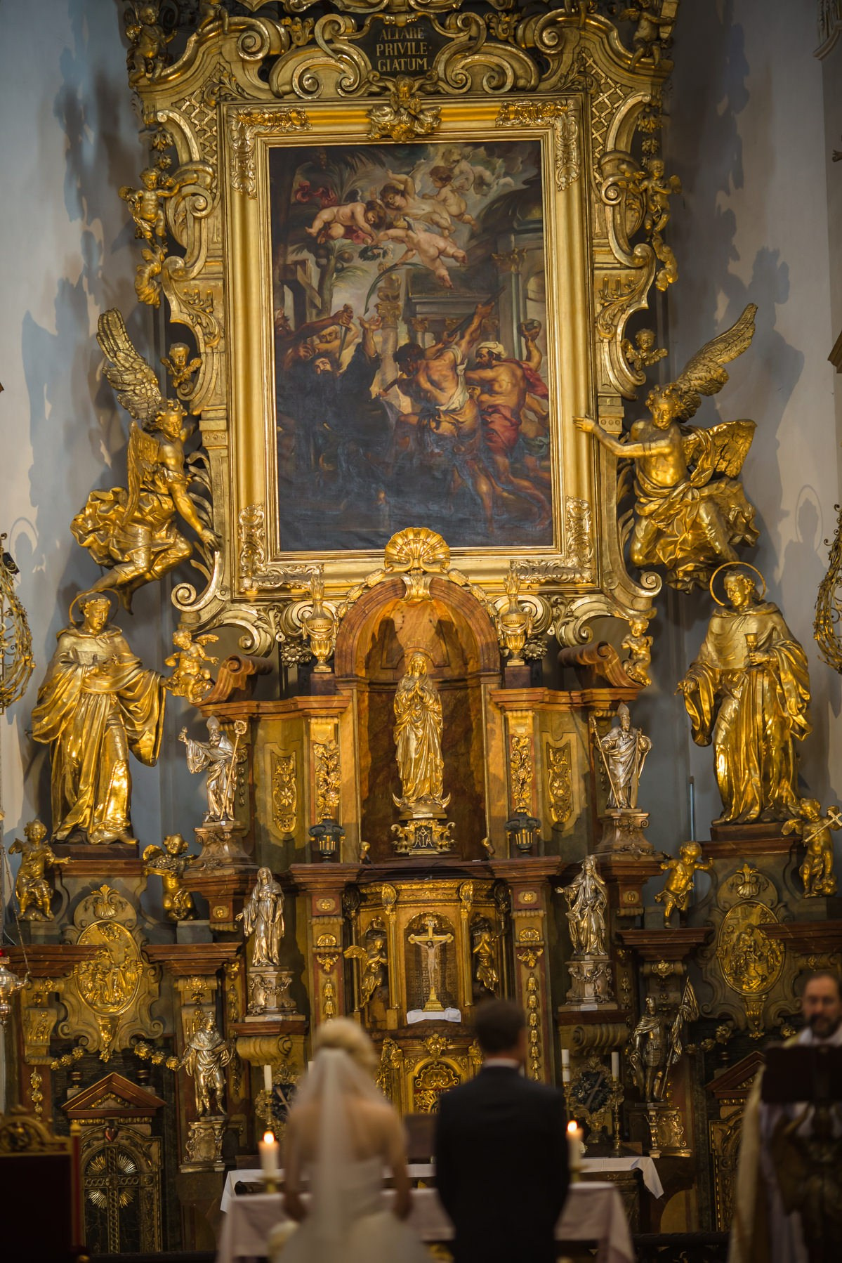 Newlyweds under golden Baroque altar St. Thomas Church Prague