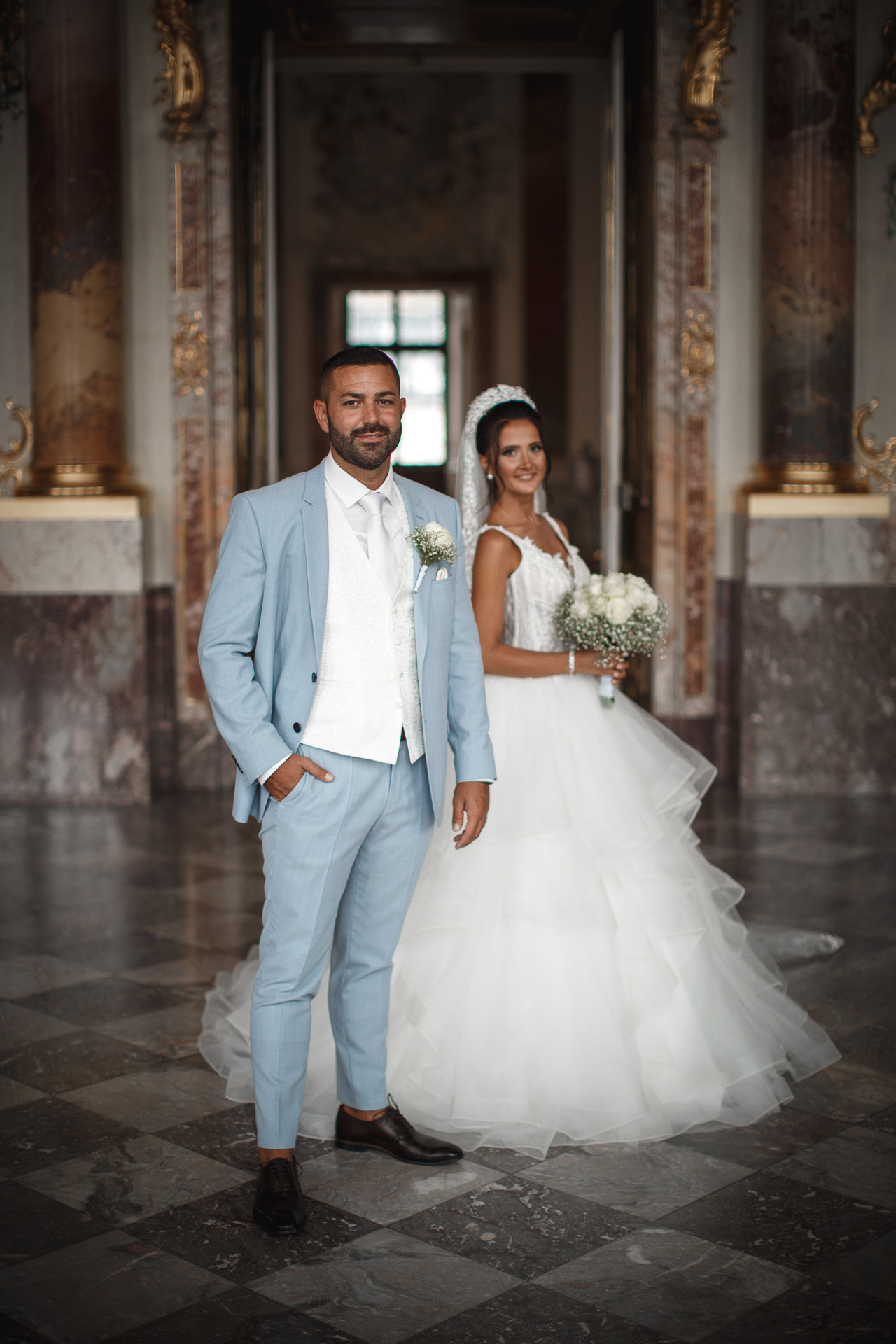 Die Braut strahlt in ihrem traumhaften Hochzeitskleid neben dem Bräutigam im Schloss Bruchsal