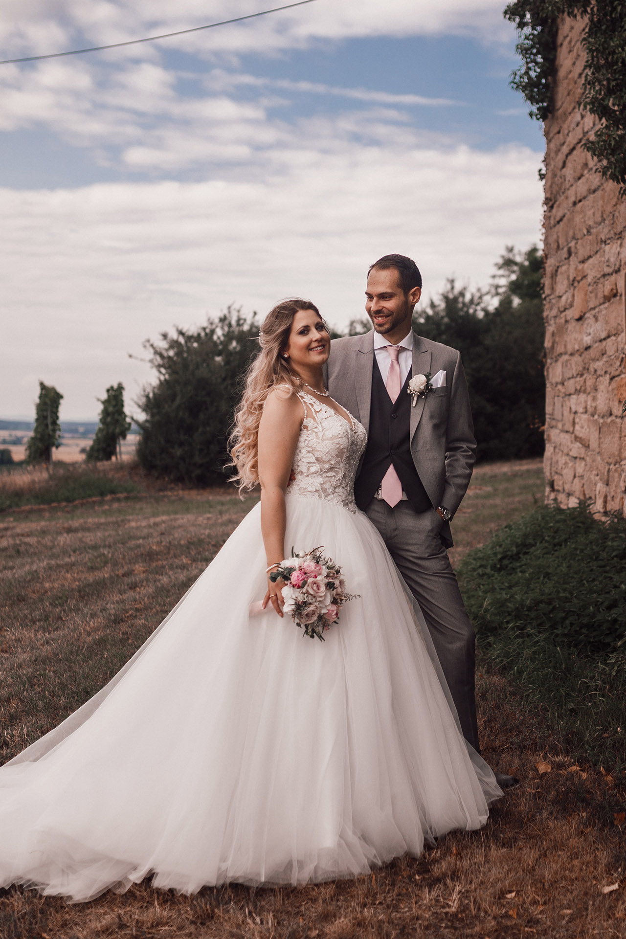 Hochzeitsfoto in der Natur – Braut und Bräutigam posieren vor malerischer Kulisse