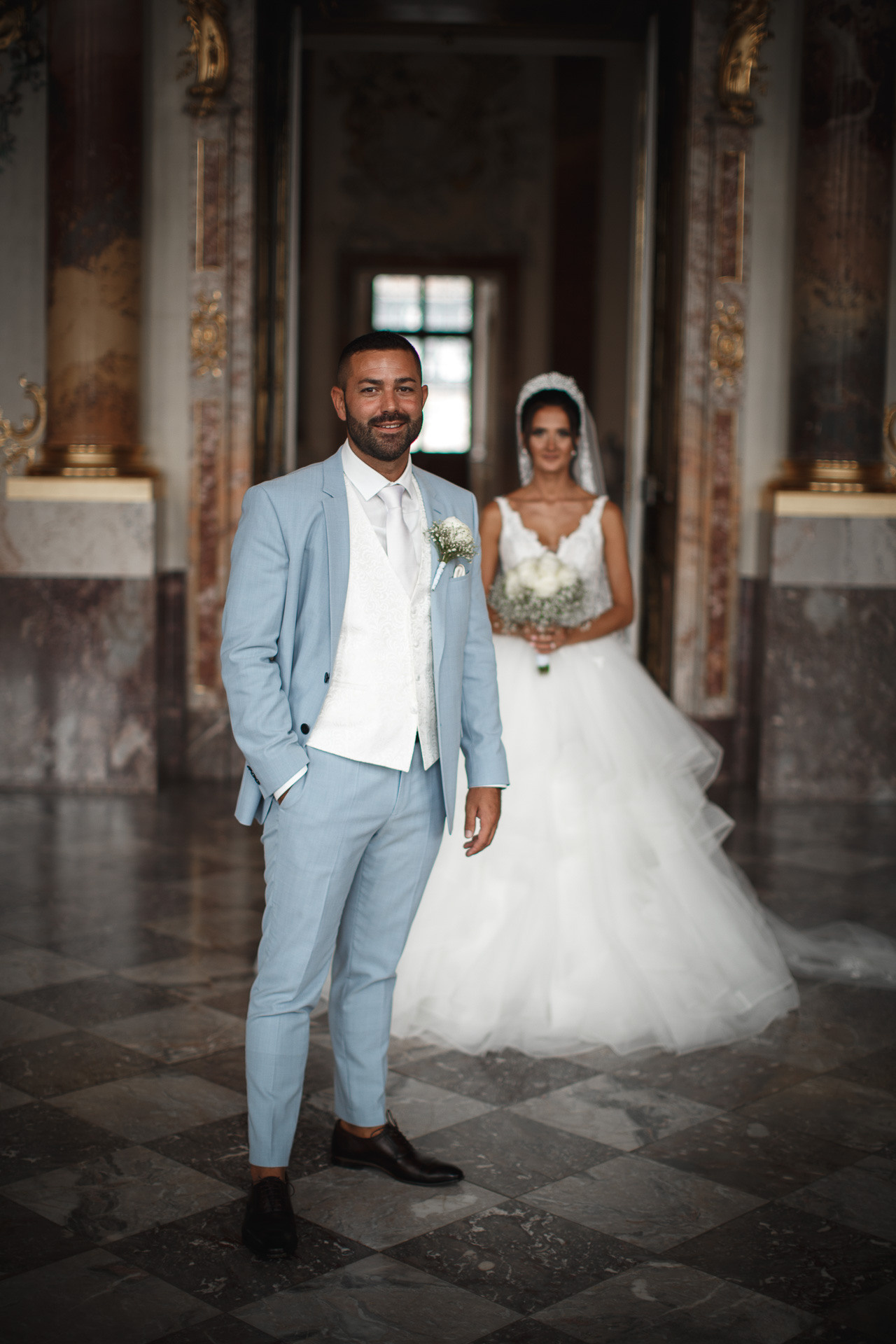 Die Braut strahlt in ihrem traumhaften Hochzeitskleid neben dem Bräutigam im Schloss Bruchsal