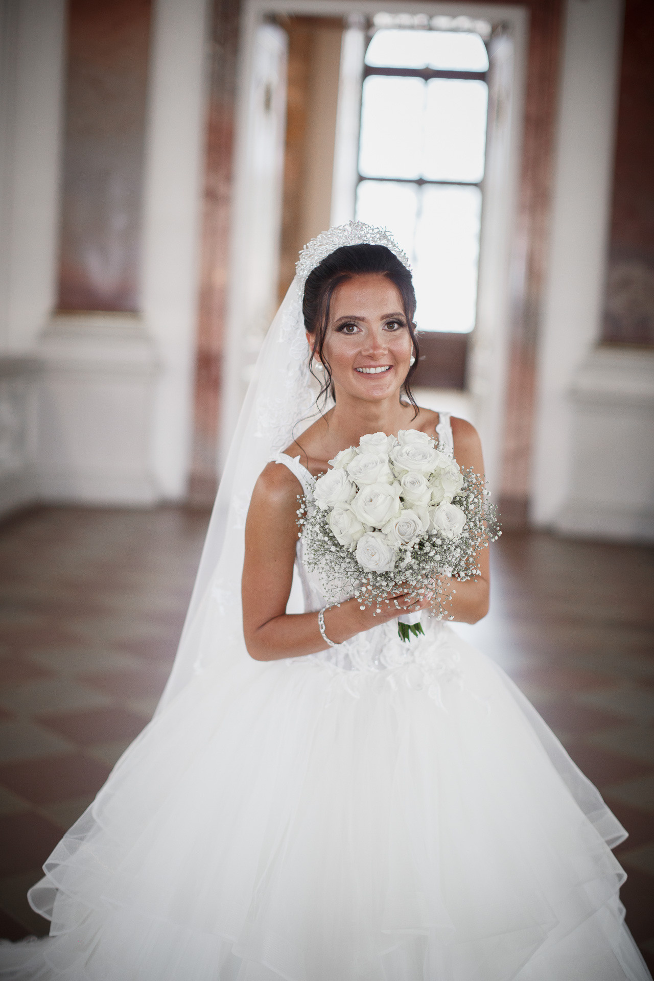 Die Braut hält ihren Brautstrauß vor dem geschichtsträchtigen Schlossgebäude.