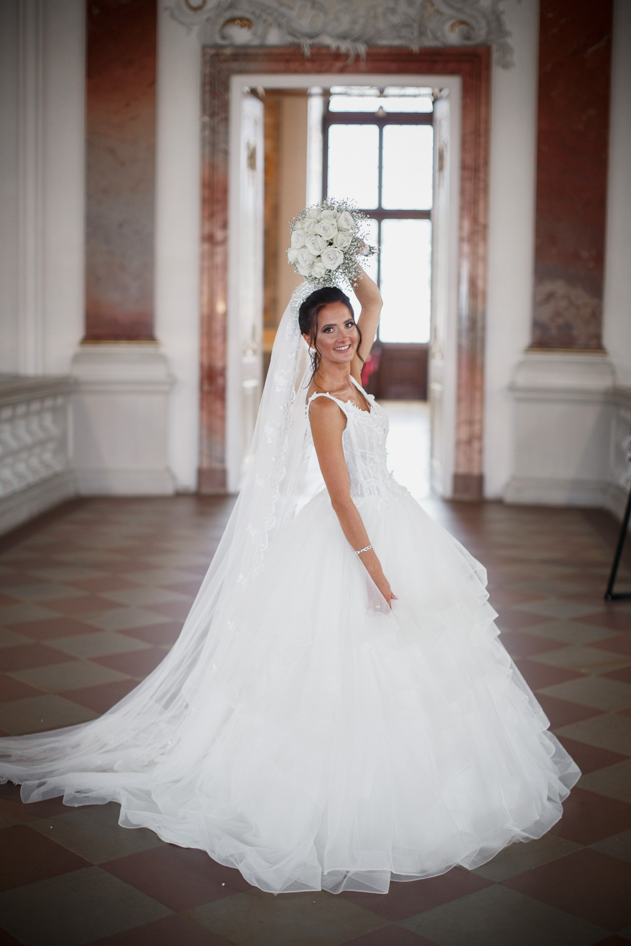 Die Braut lächelt verträumt und hält ein Bouquet aus Blumen in den Händen.