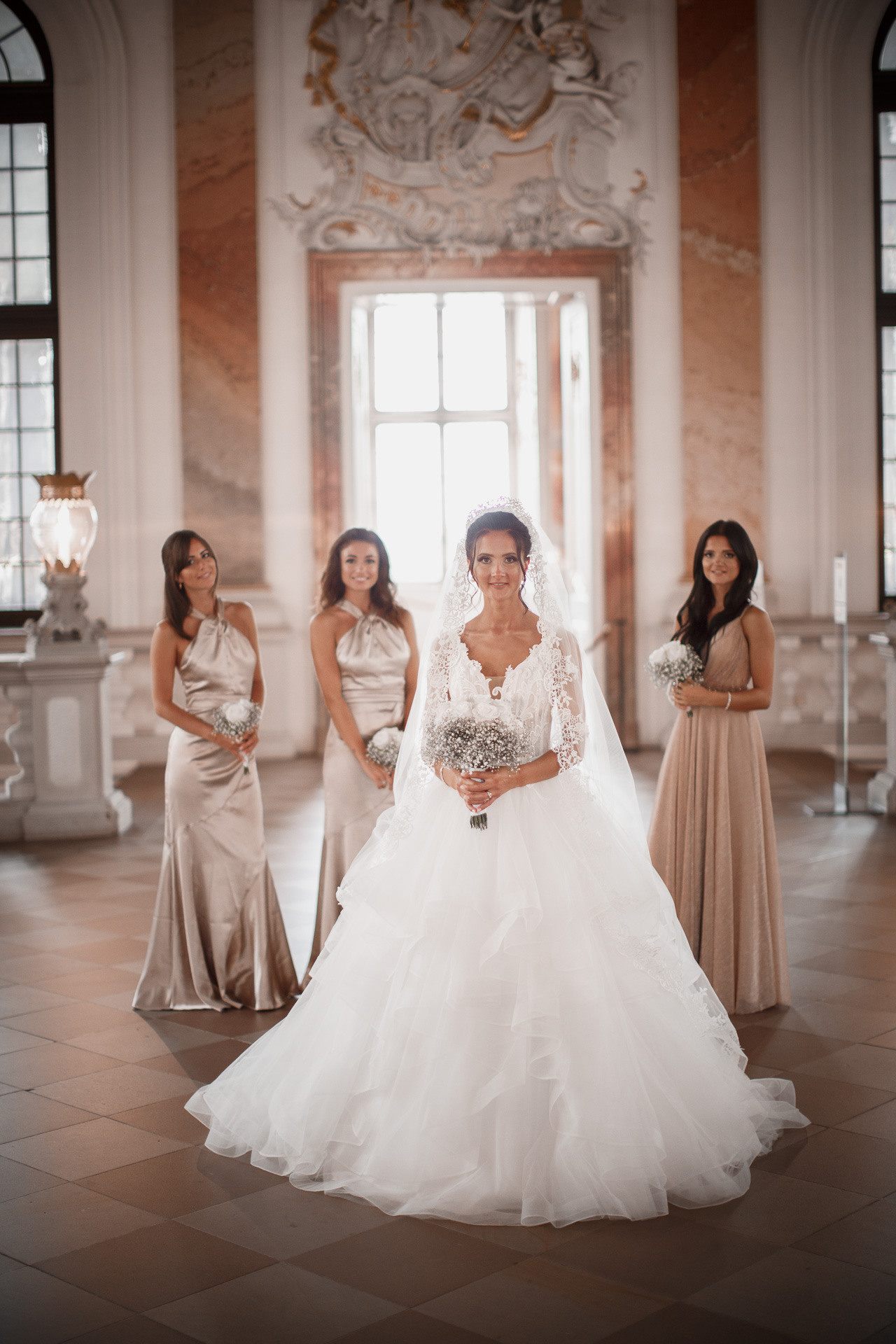 Romantisches Gruppenfoto: Die Braut und ihre Brautjungfern posieren mit Blumensträußen vor den historischen Schlossmauern.